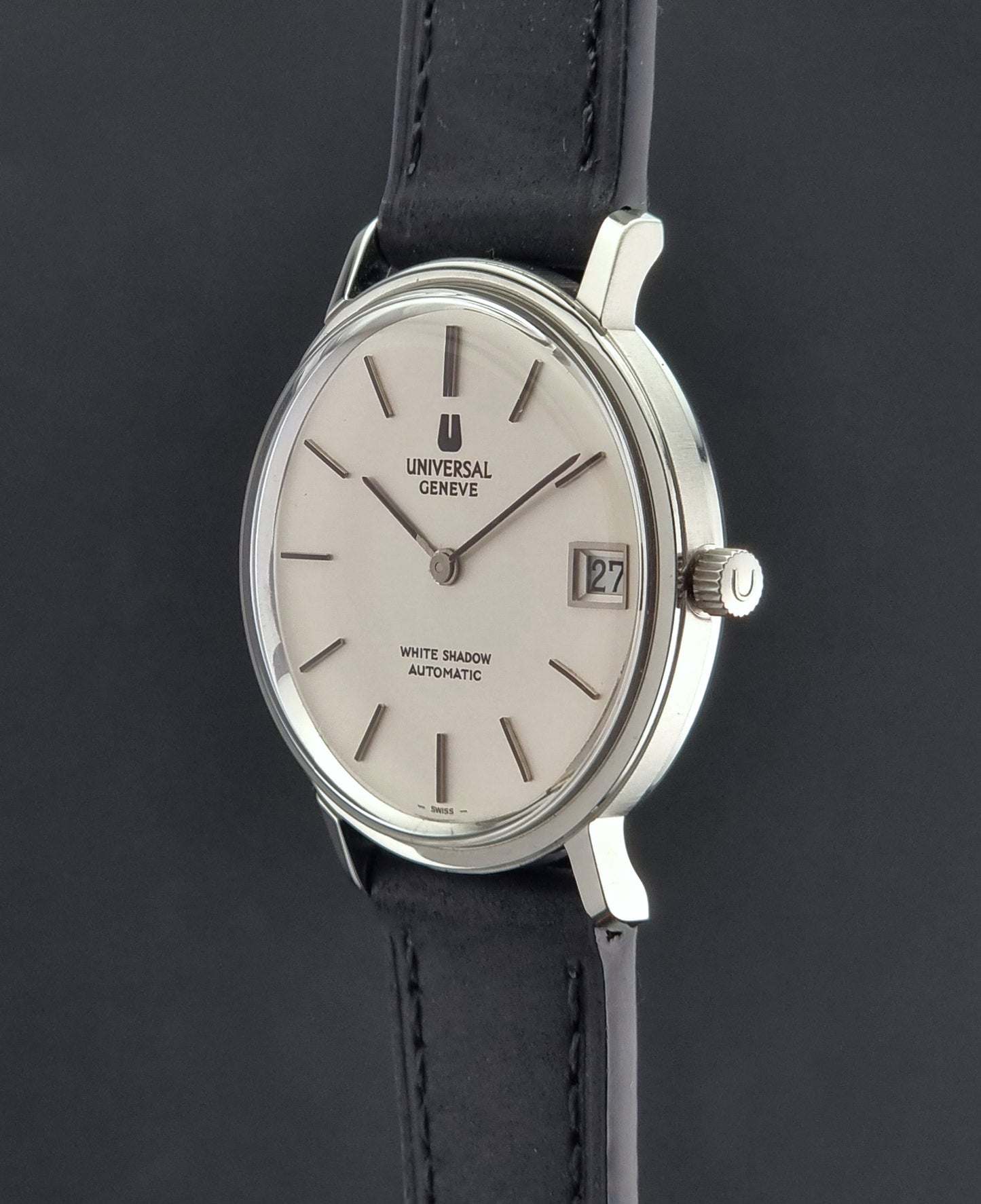Universal Geneve watch with silver case and black leather strap on a dark background