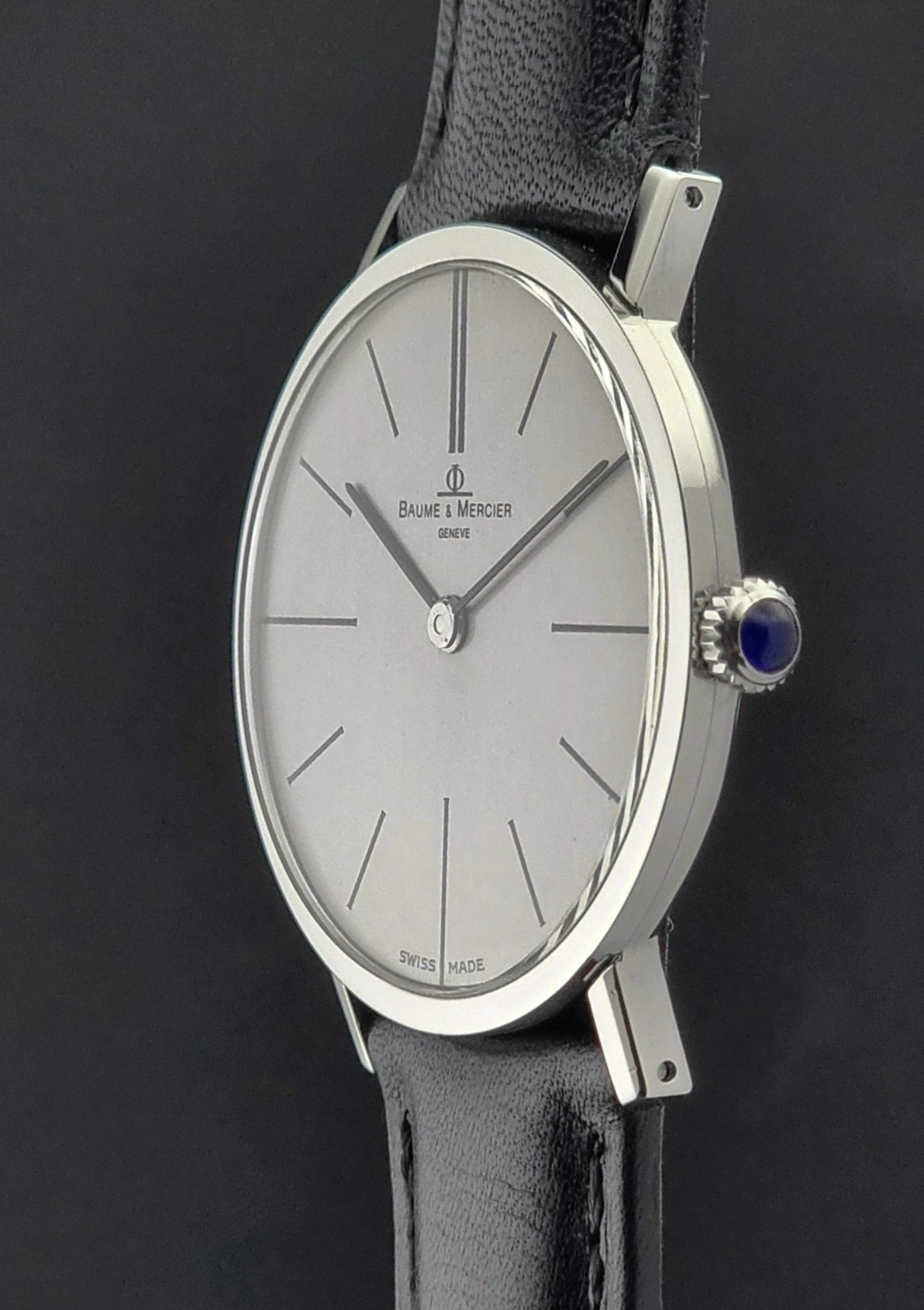Baume & Mercier watch with silver dial and black leather strap on a dark background
