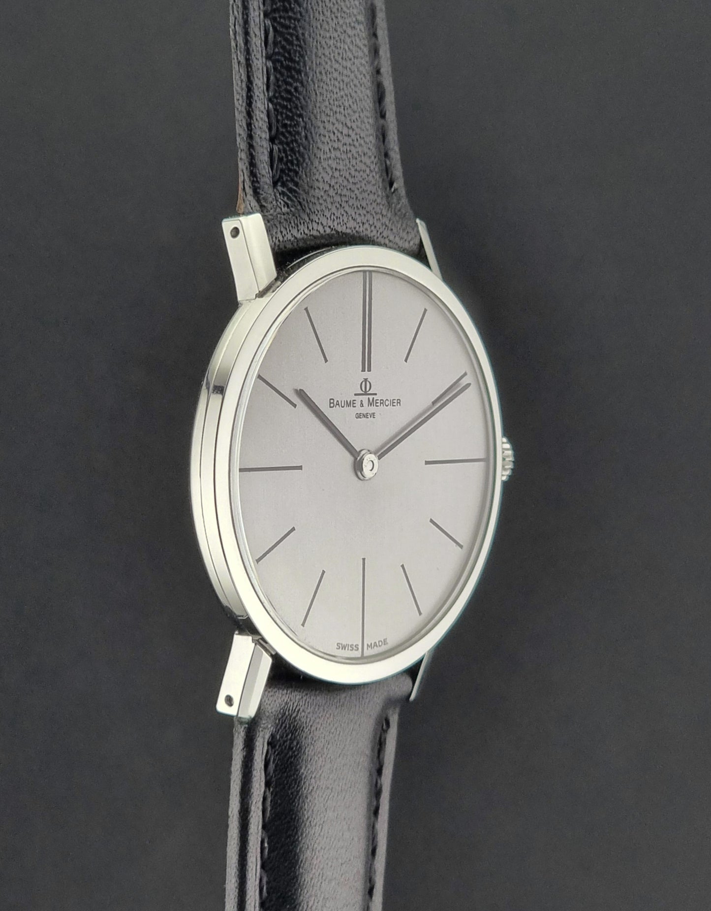 Baume et Mercier Wristwatch with black leather strap and silver case on a dark background
