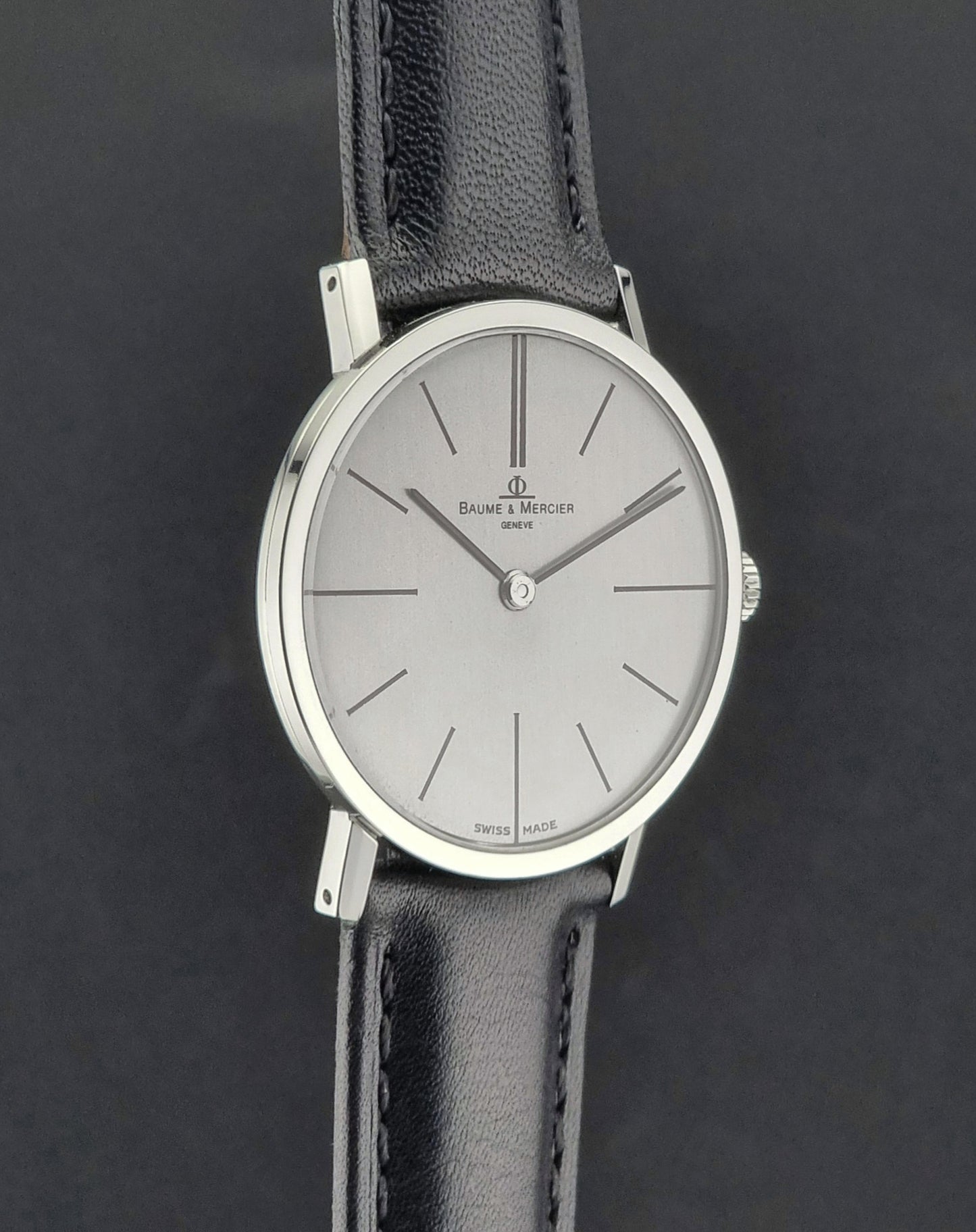 Baume et Mercier Wristwatch with black leather strap and silver case on a dark background
