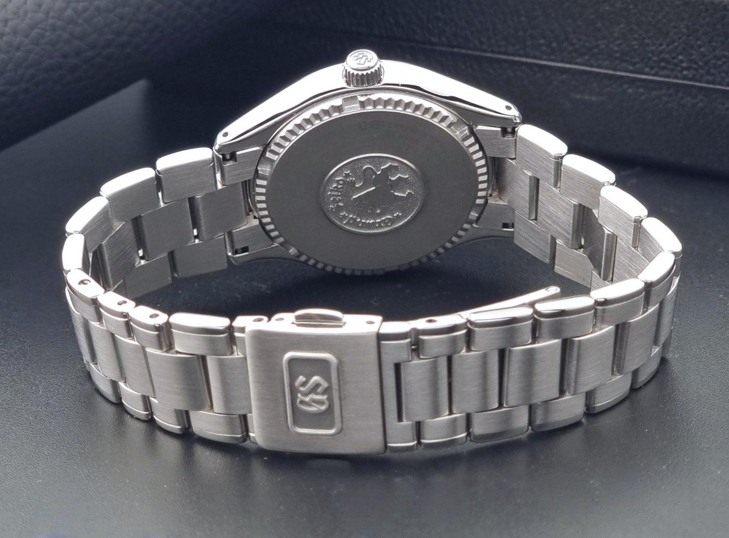 A Grand Seiko SBGX005 quartz watch 9F62-0A10 Sunburst Dial with bracelet on a dark back ground a back view