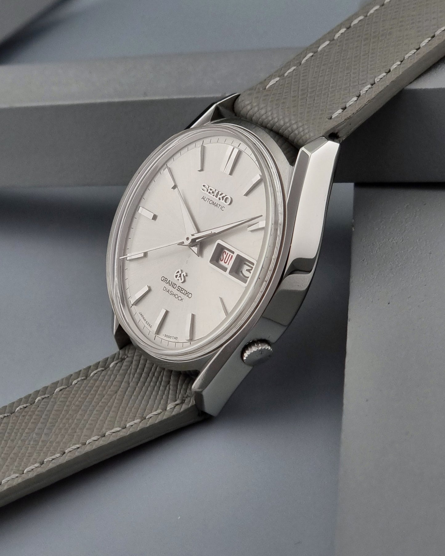 Vintage Grand Seiko watch with a gray strap on a gray surface