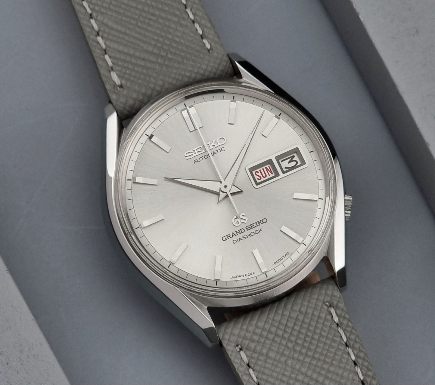 Grand Seiko watch with gray strap on a gray background