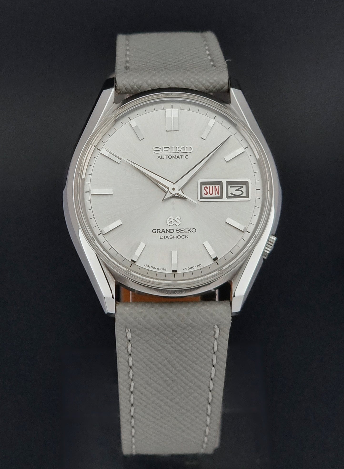 Vintage Grand Seiko watch with gray leather strap on a black background