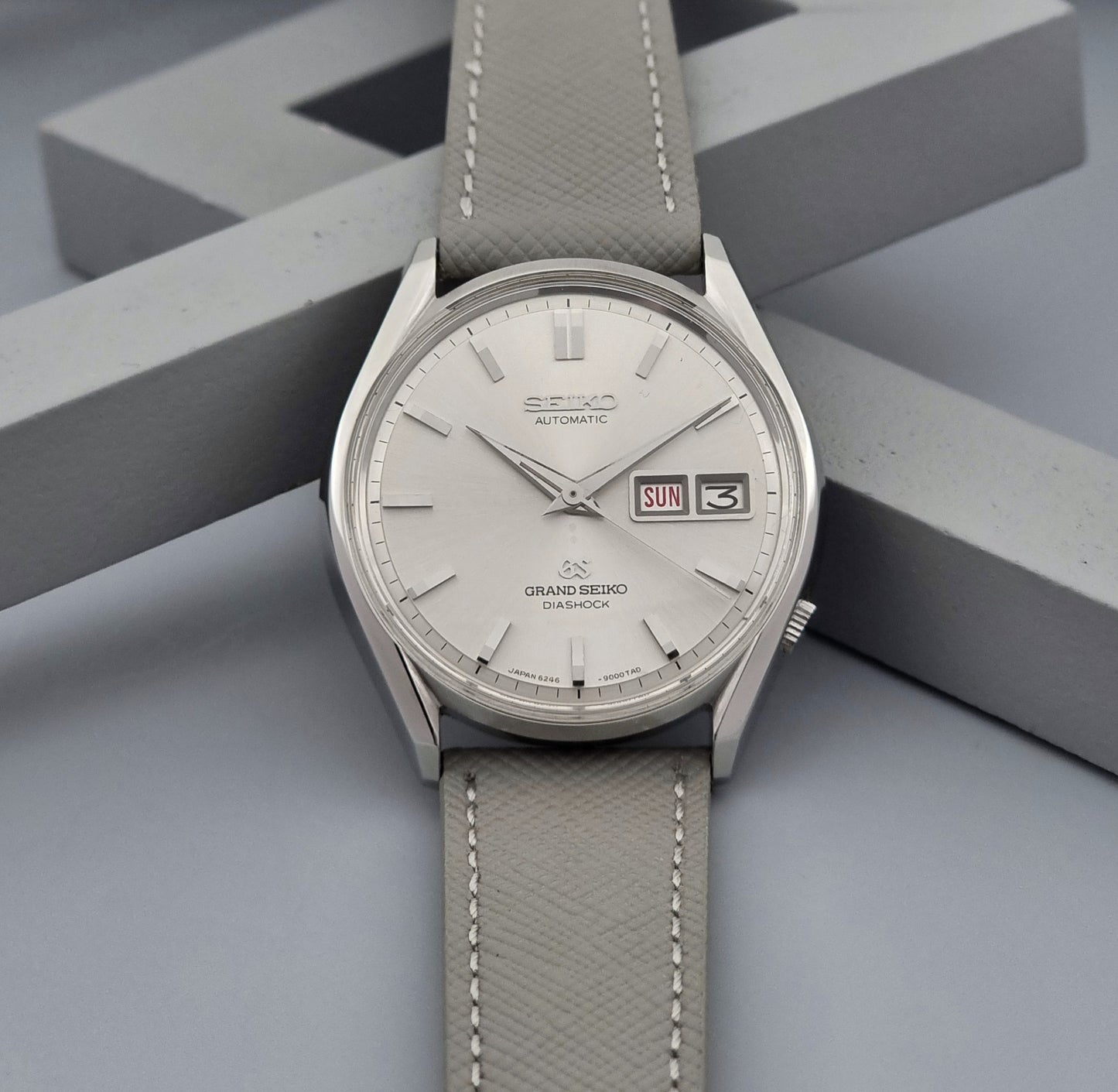 Grand Seiko watch with gray strap on a geometric gray background