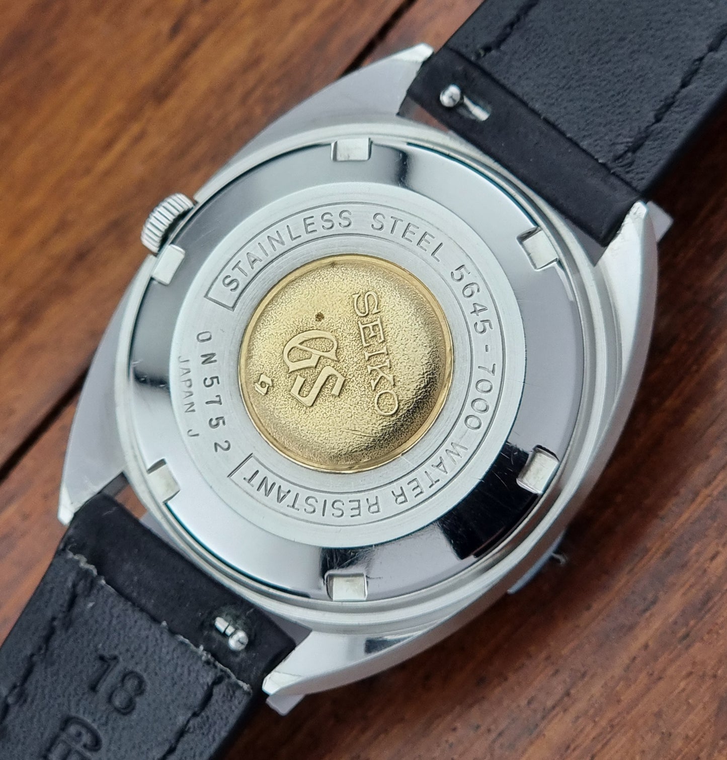 Grand Seiko Watch case with brand logo on a wooden surface