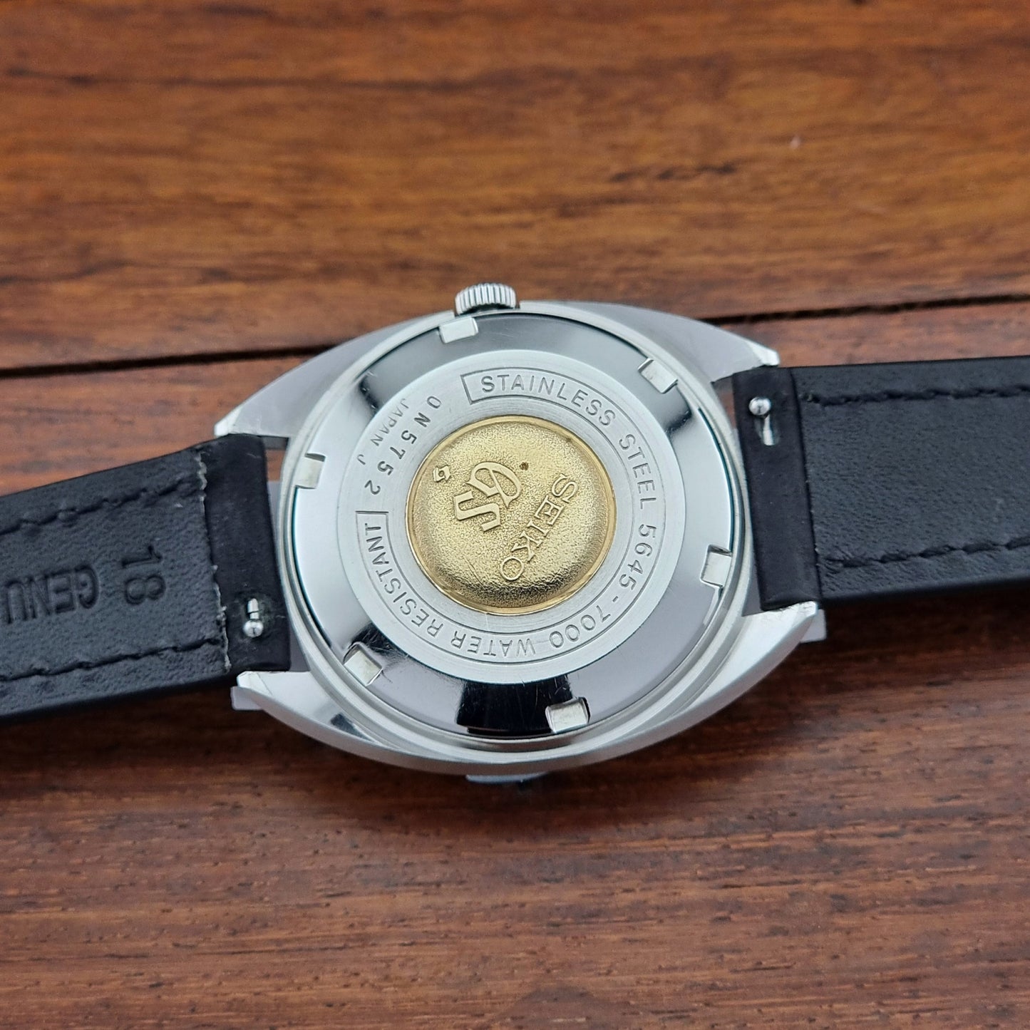 Watch case with brand logo on a wooden surface
