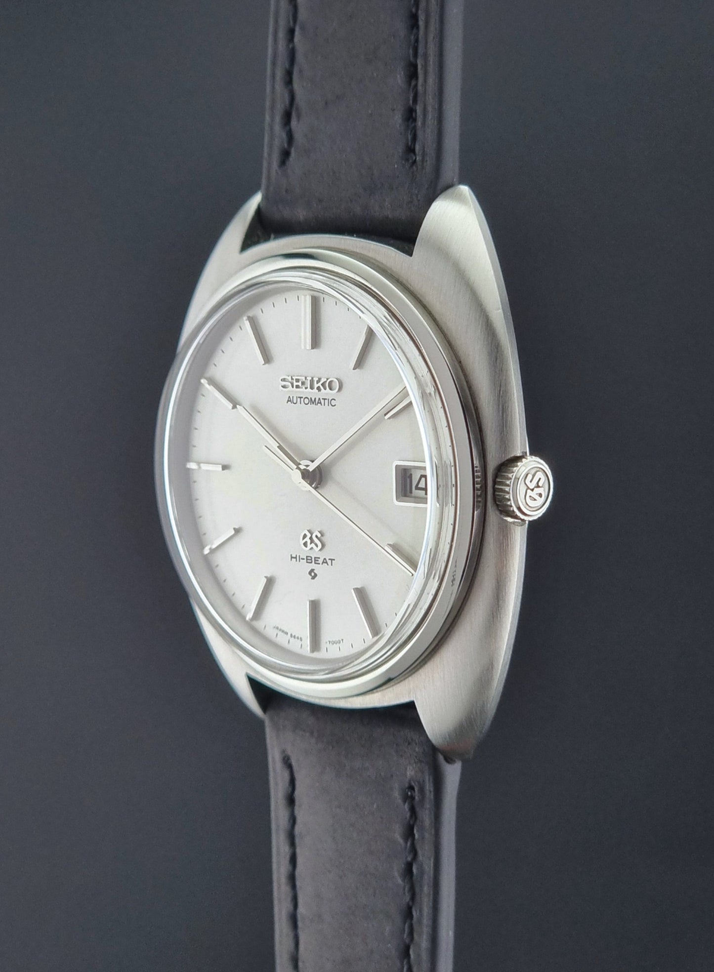 Grand Seiko watch with silver dial and black leather strap on a dark background