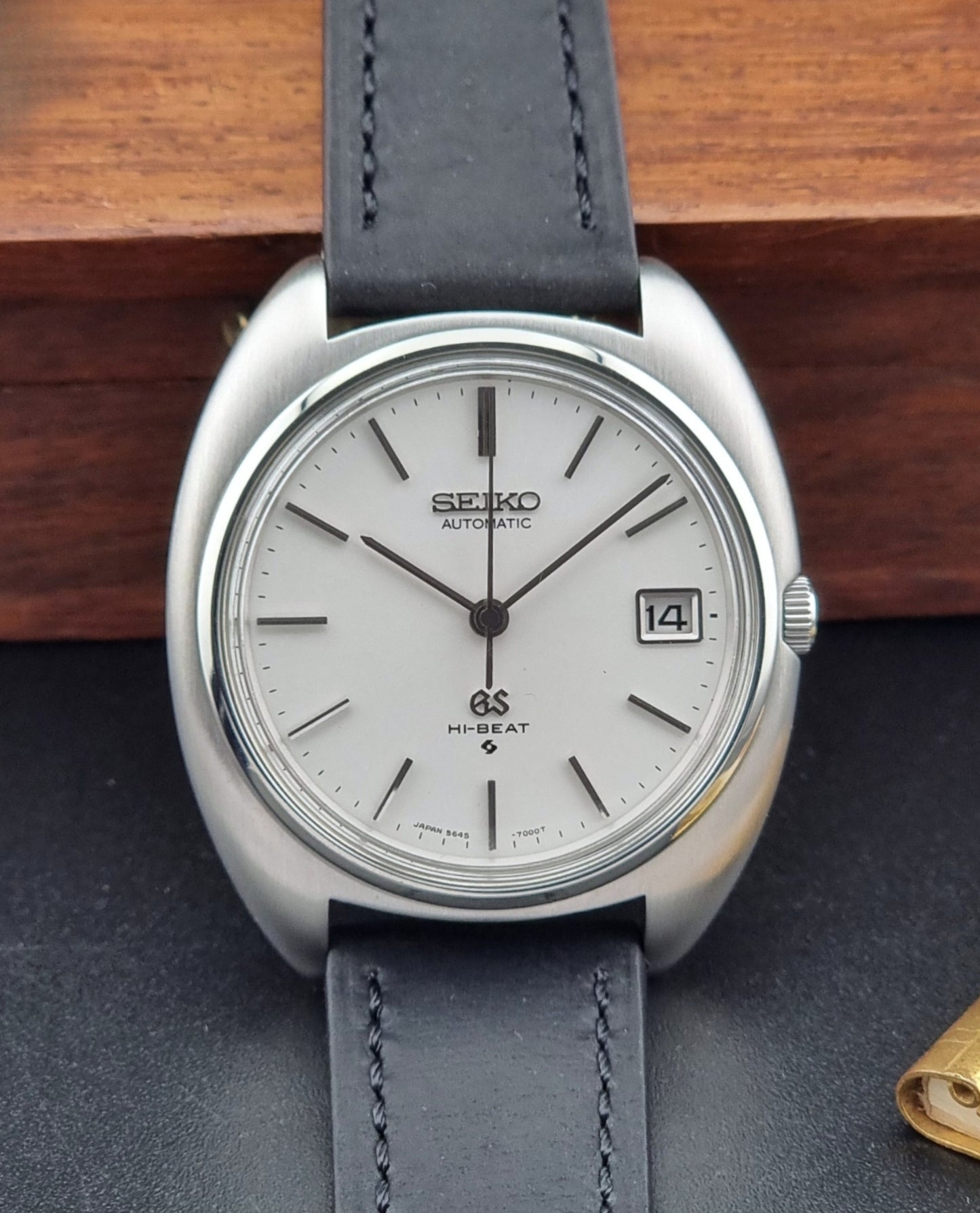 Grand Seiko watch with gray leather strap on a wooden surface