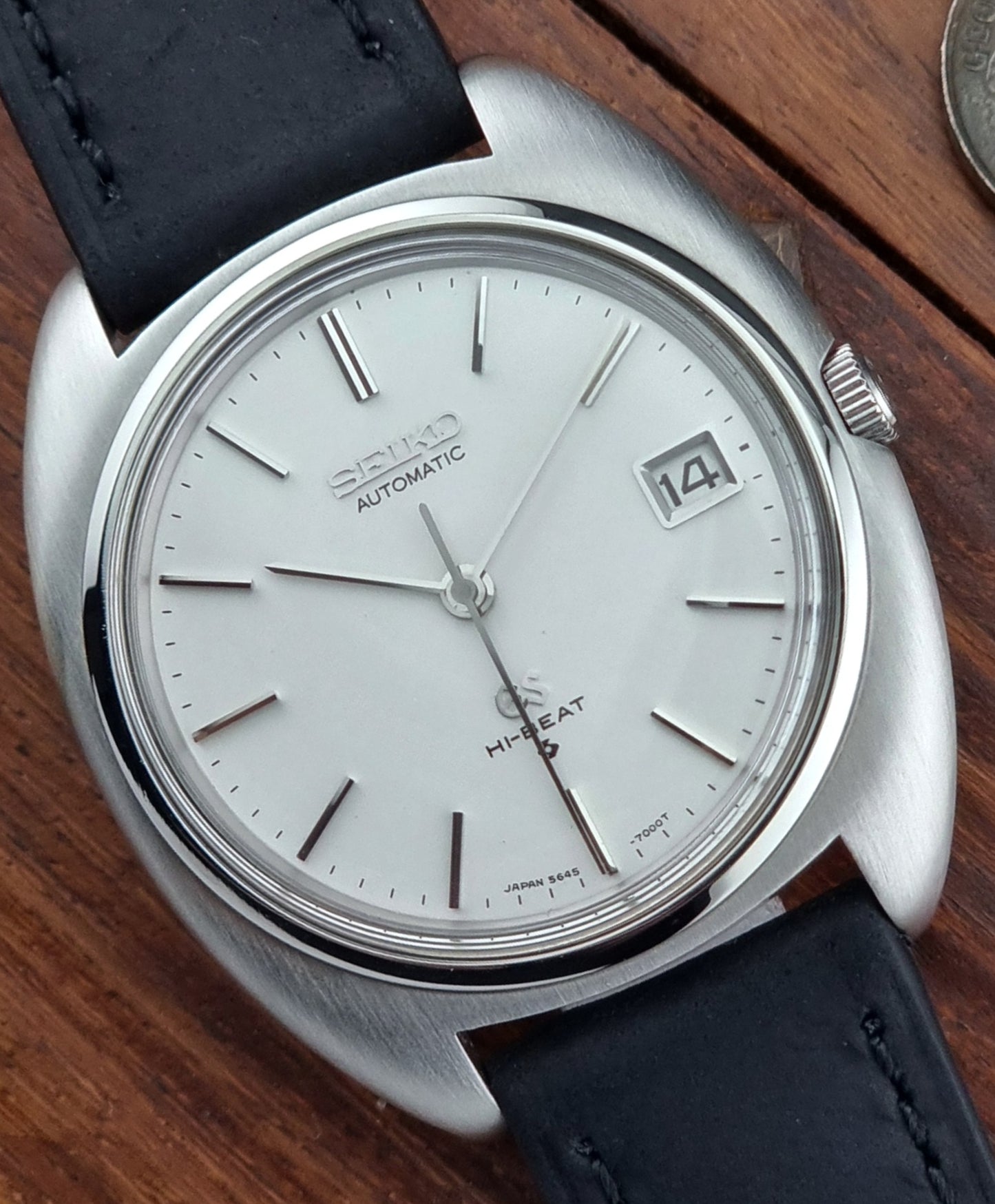 Vintage Grand Seiko watch with black leather strap on a wooden surface