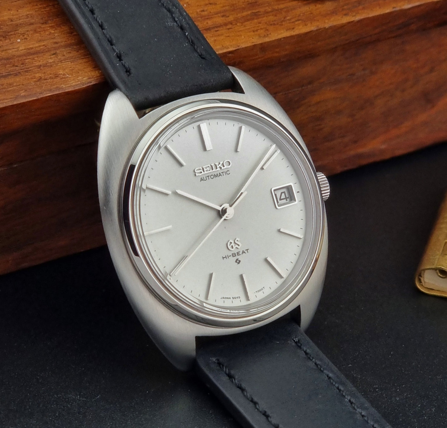 Grand Seiko watch with black leather strap on a wooden surface