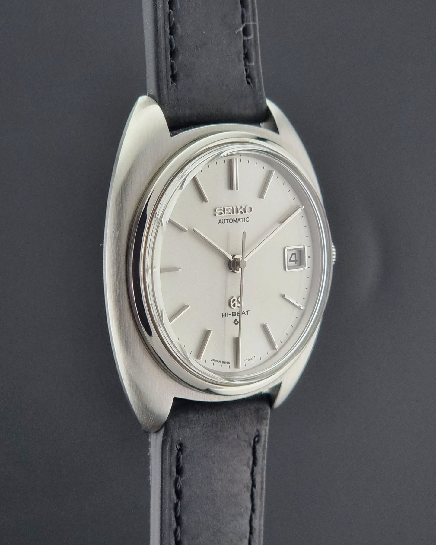 Grand Seiko watch with silver dial and black leather strap on a dark background
