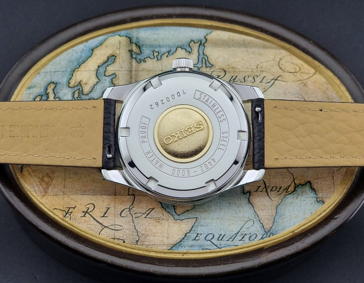 Vintage King Seiko Wristwatch with black leather strap on an old map background case back view