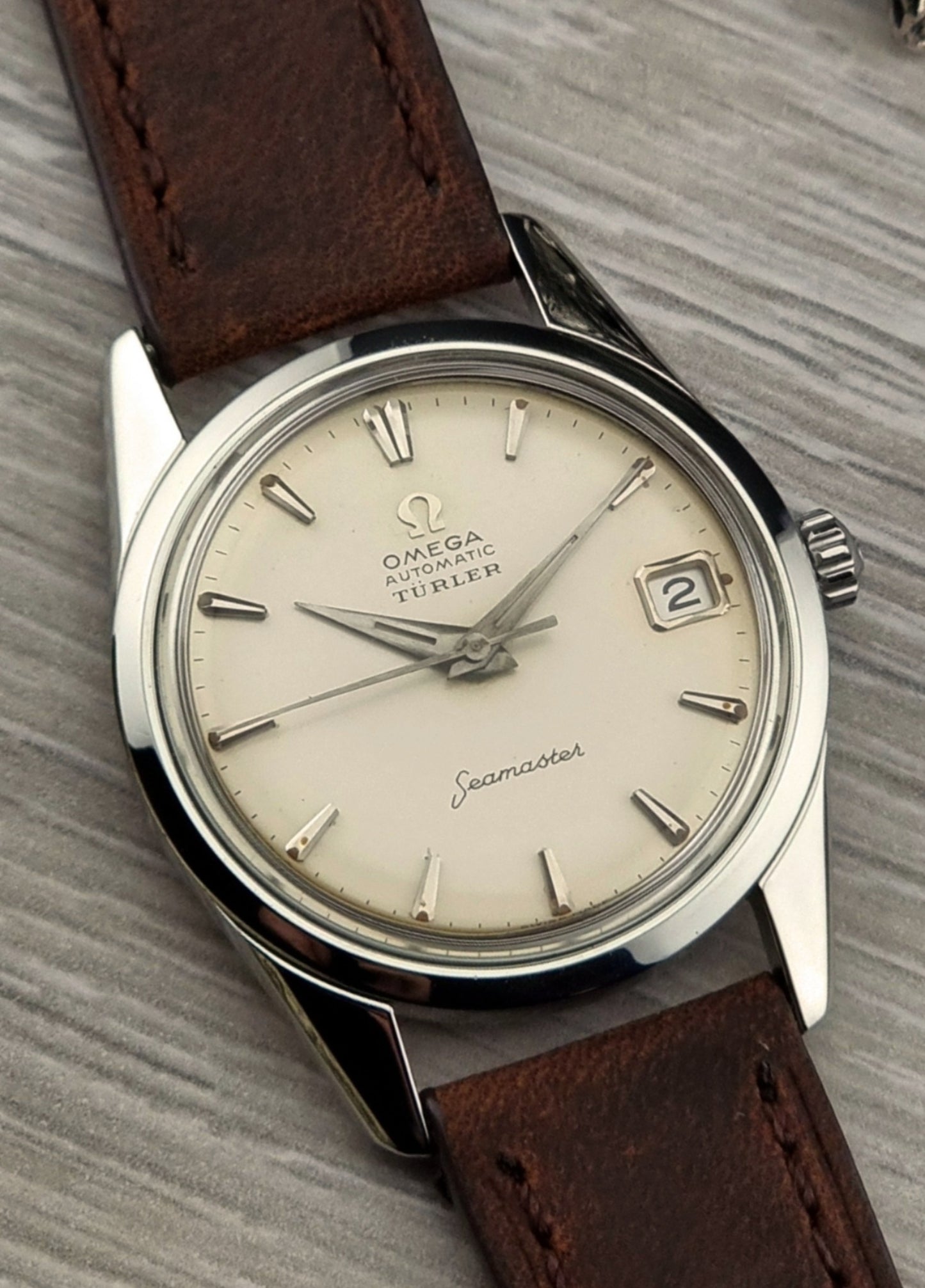 A vintage Omega Seamaster watch with a Turler co-signed dial with brown leather strap on a textured surface