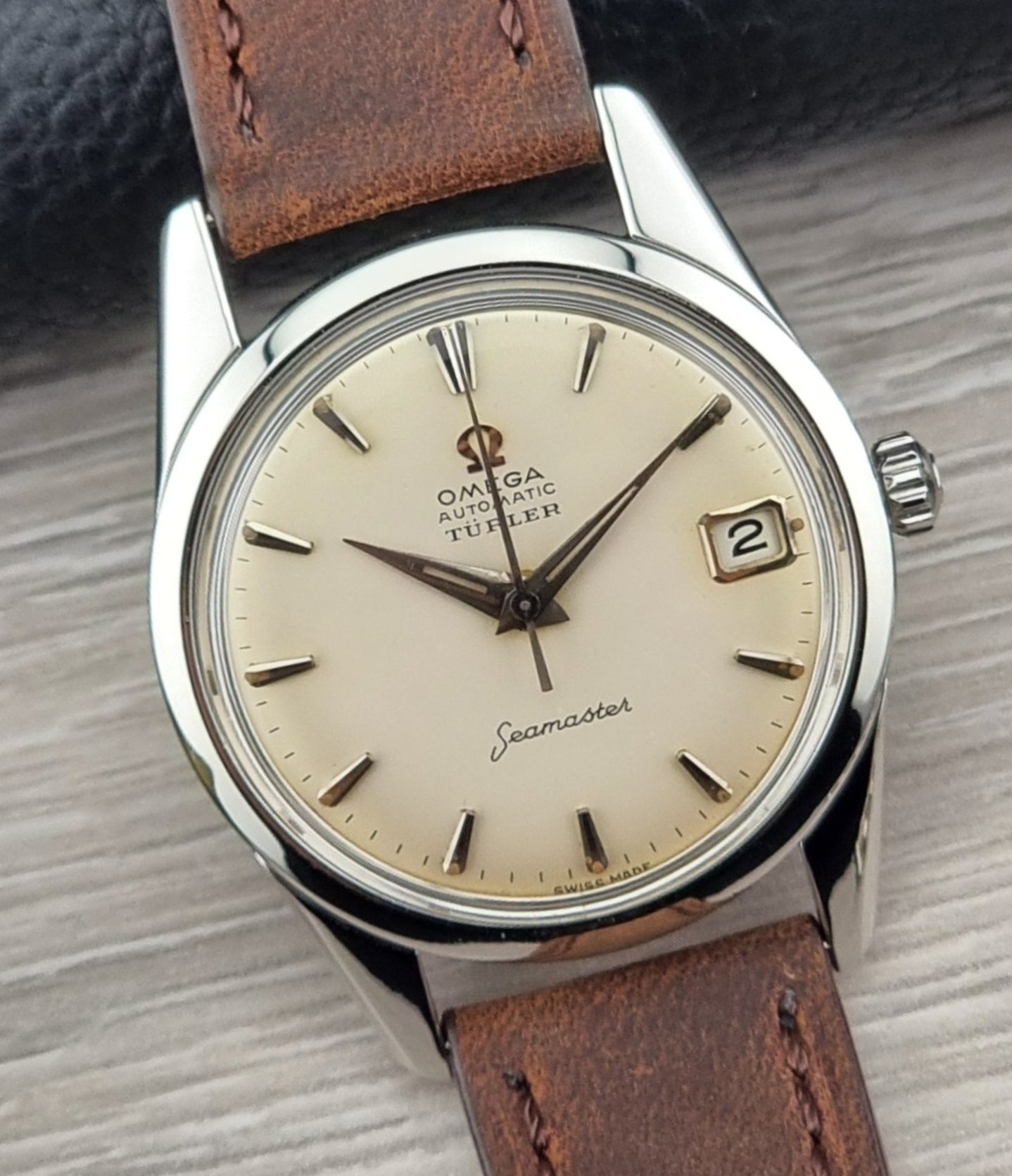 Vintage Omega Seamaster watch with brown leather strap on a textured surface