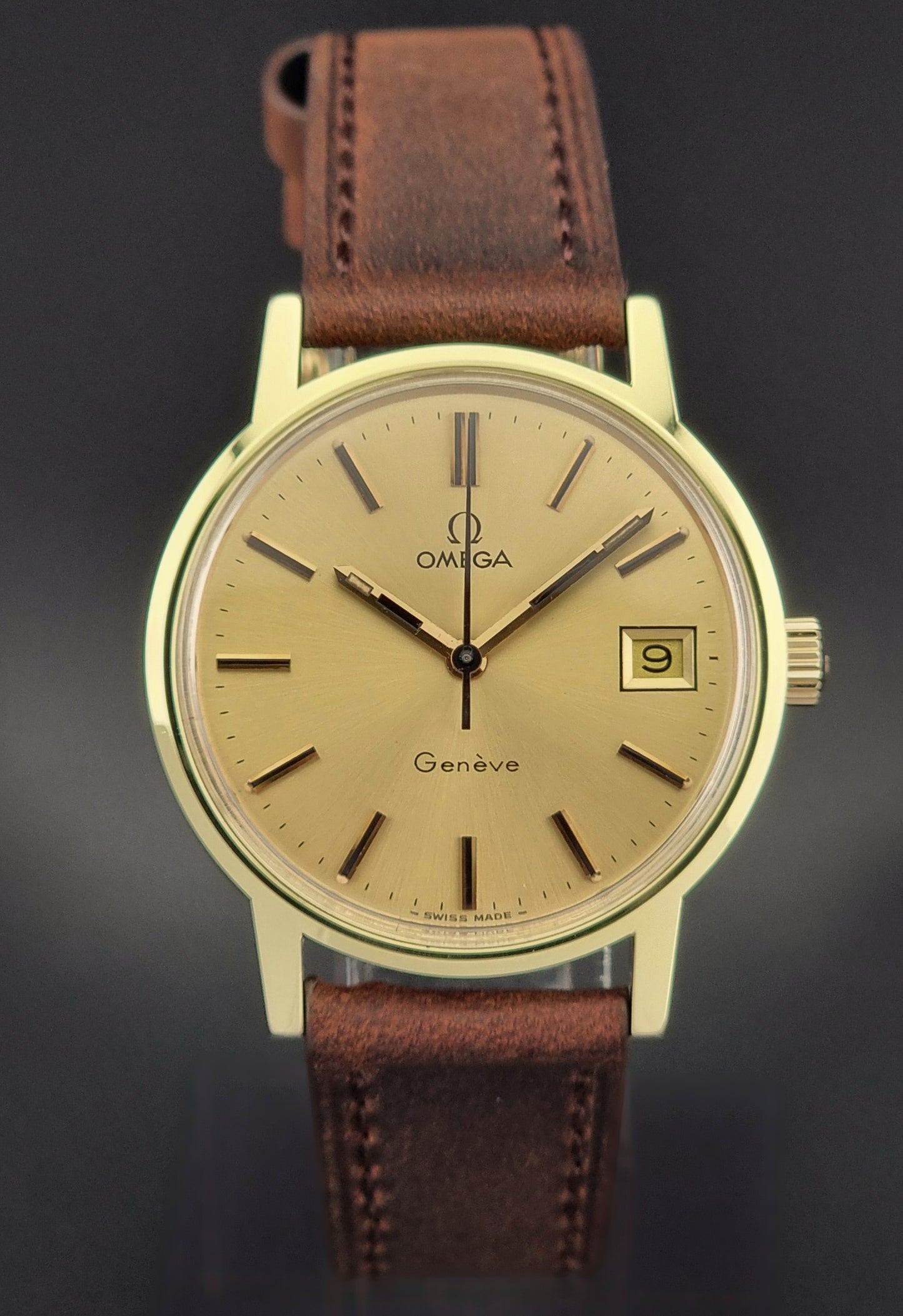Vintage Gold Omega Geneve watch with brown leather strap on a dark background