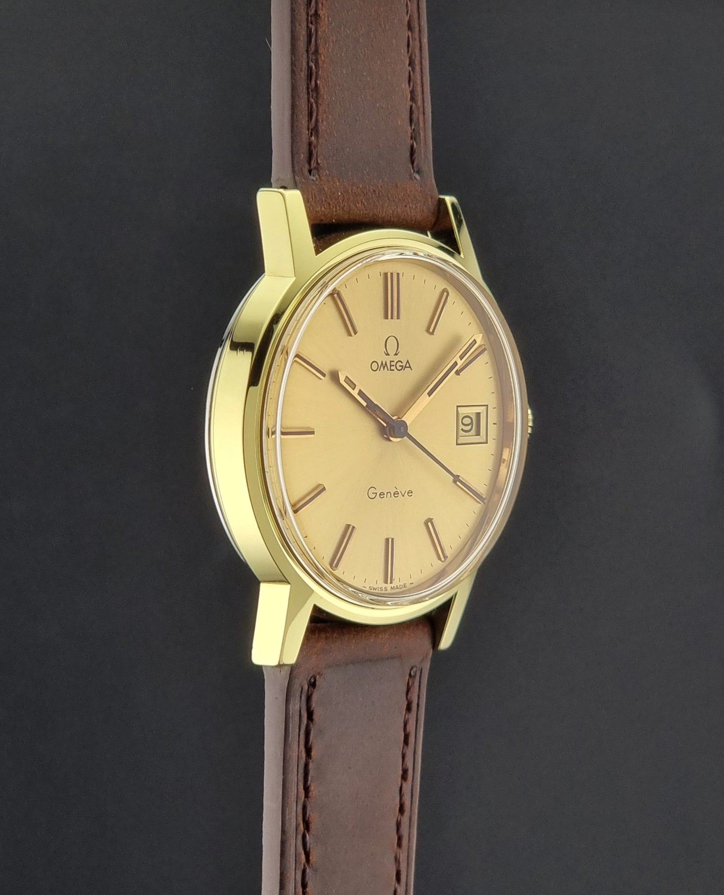 Vintage Gold Omega Geneve watch with brown leather strap on a dark background