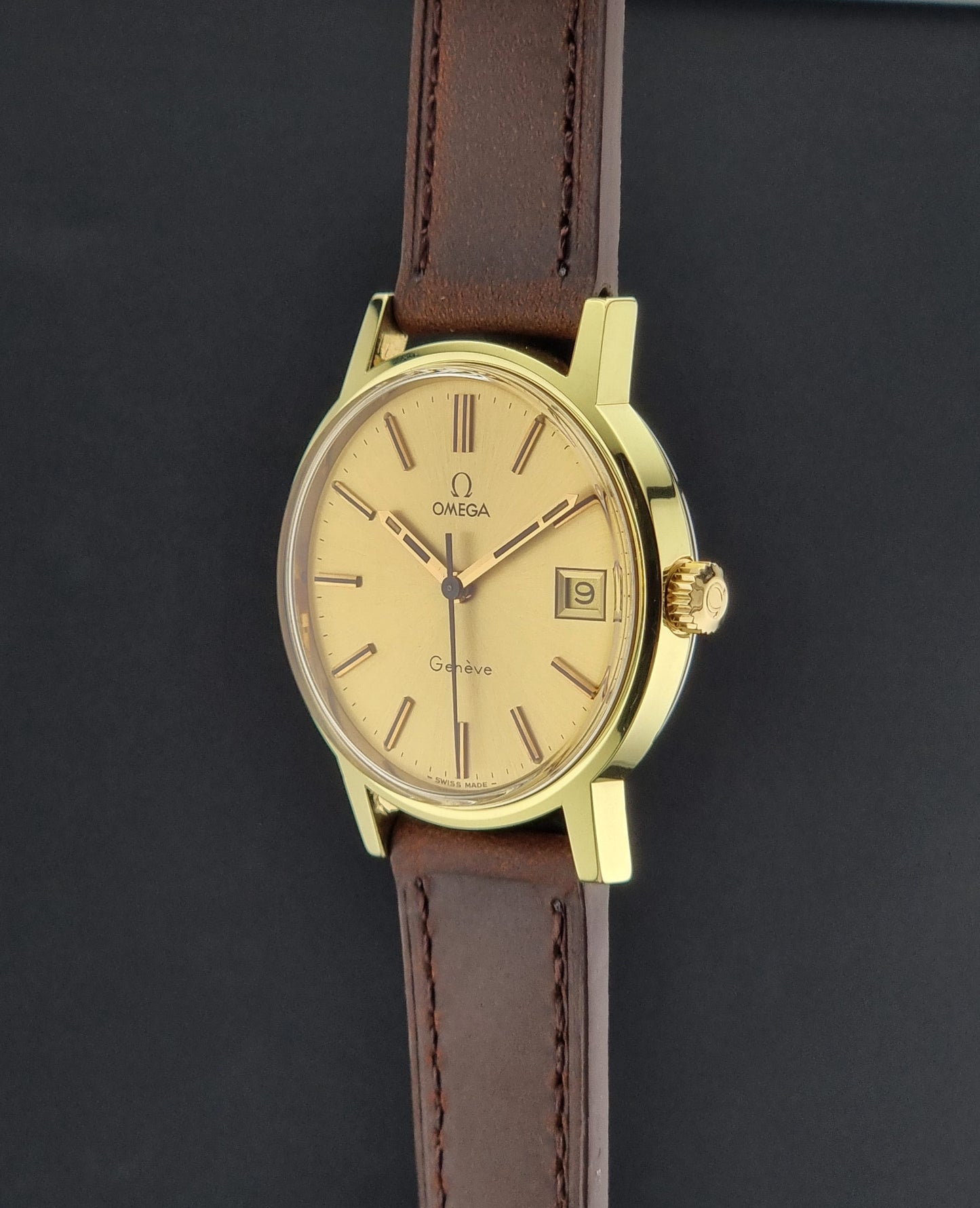 Vintage Gold Omega Geneve with a brown leather strap on a dark background