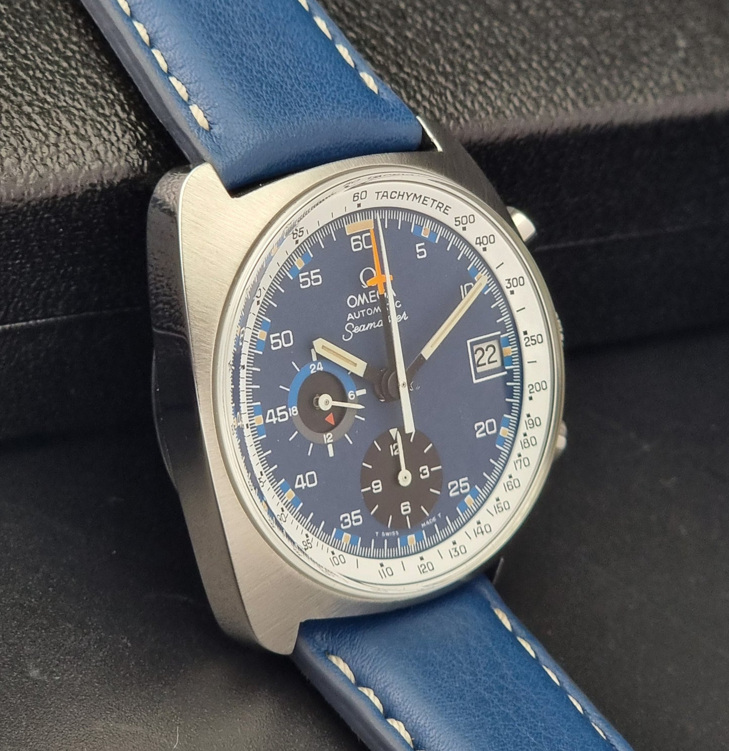 Vintage Omega Seamaster Wristwatch with blue strap and detailed face on a dark textured background