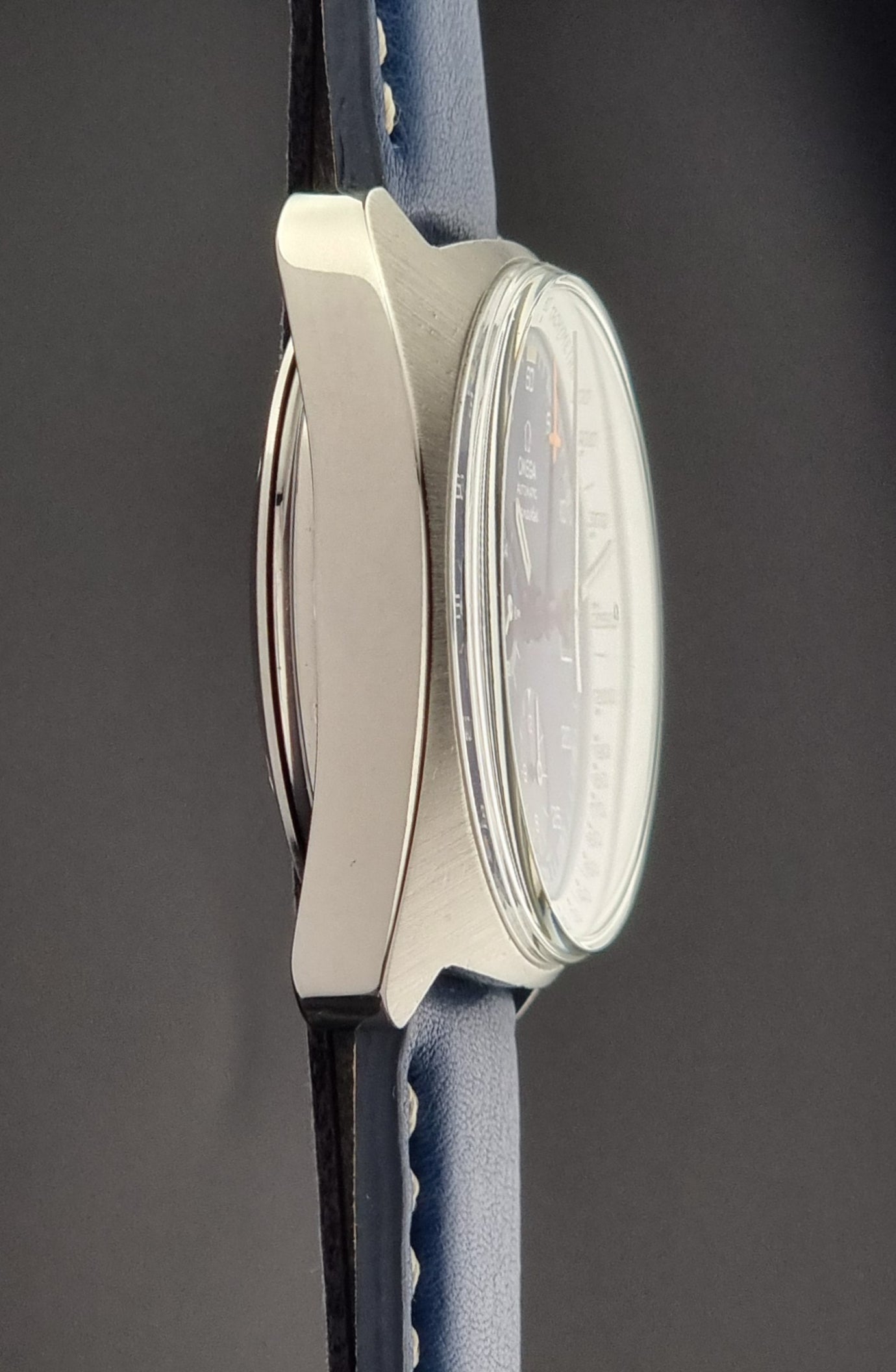 Vintage Omega Seamaster watch with a blue strap and white face on a dark gray background