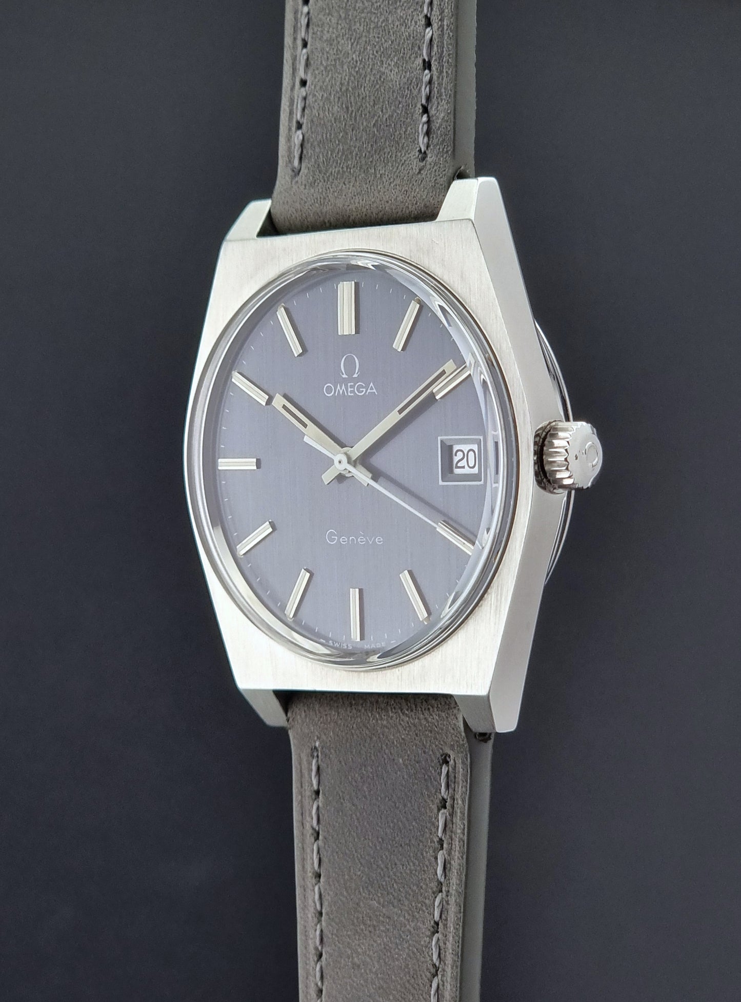 Vintage Omega Geneve watch with gray leather strap on a dark background