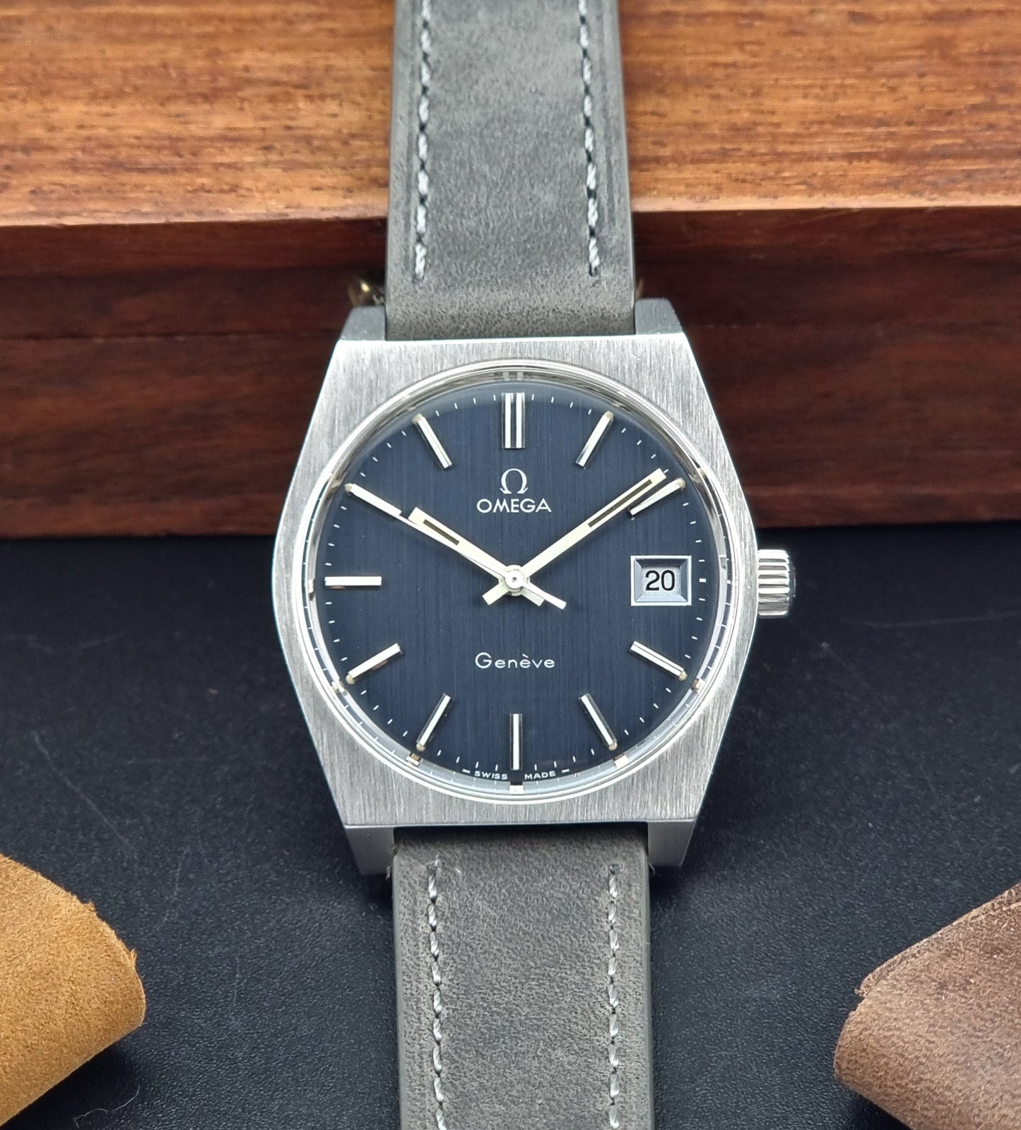Vintage Omega Geneve watch with blue dial and gray strap on a dark surface