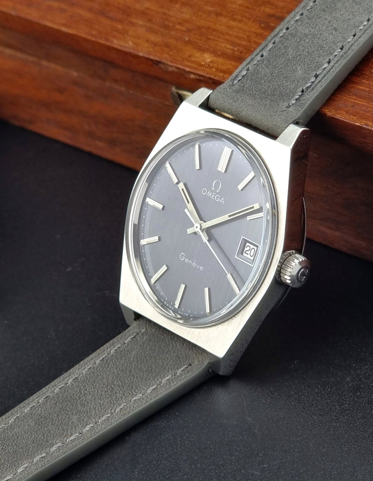 Vintage Omega Geneve watch with gray strap and gray dial on a dark surface