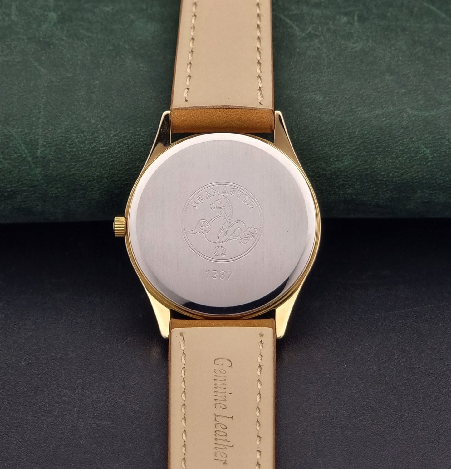 Vintage Omega Quartz Wristwatch Seamaster 196.0281 with a brown leather strap on a dark gray background case back view