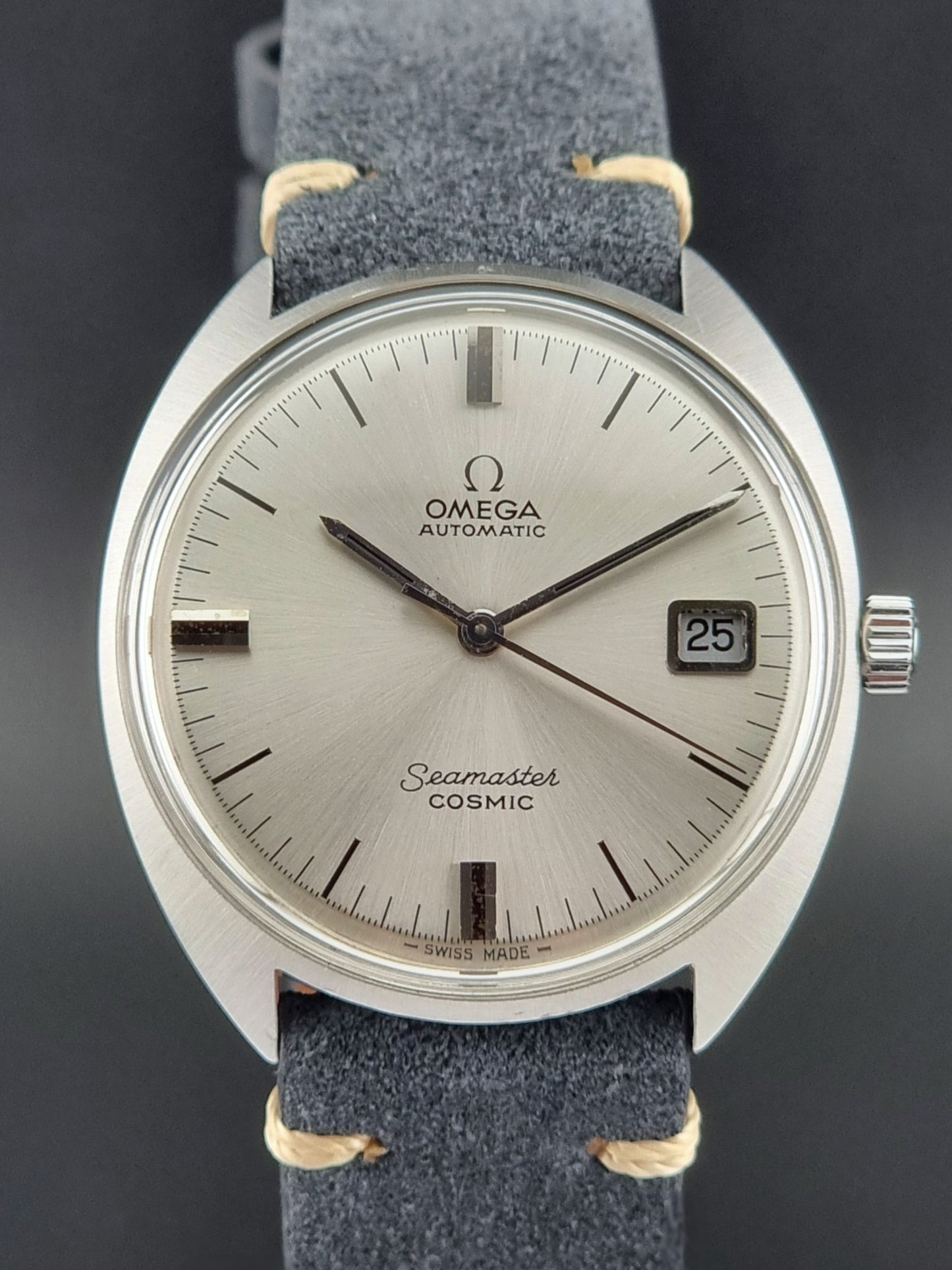 Vintage Omega Seamaster Cosmic watch with silver dial and blue strap on a dark background