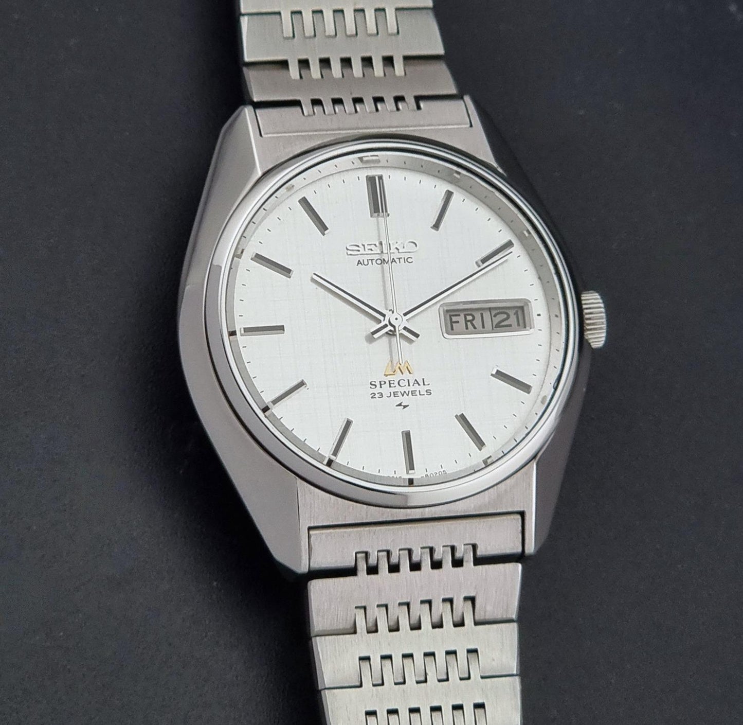 A Vintage Seiko LordMatic Special 5216-8020 Wristwatch photographed on a dark textured background. The watch features a day-date window at 3 o'clock.