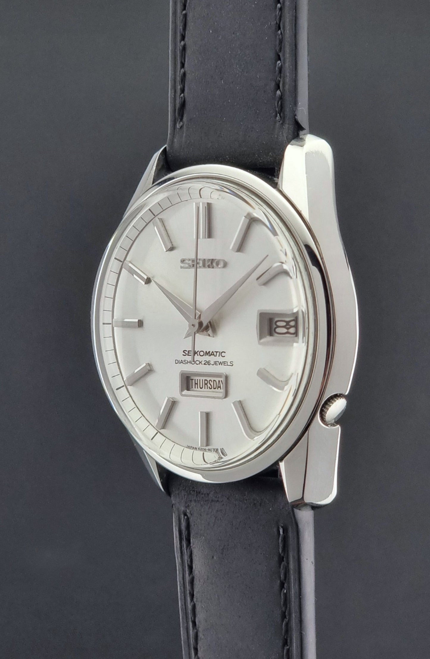 Seiko Seikomatic 6206-8040 Wristwatch with silver dial and black leather strap on a dark background