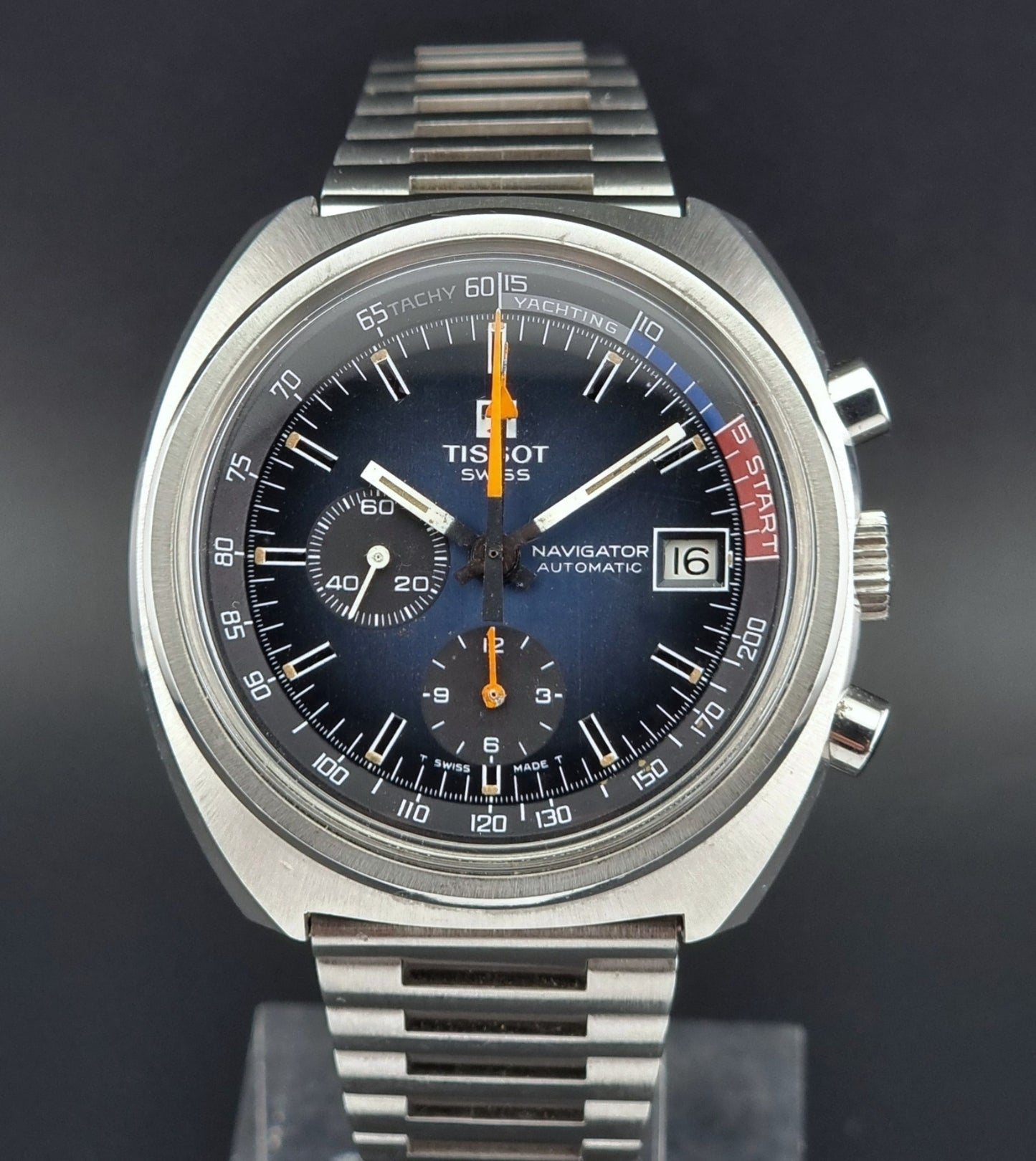 Tissot watch with a dark face and silver metal band on a black background