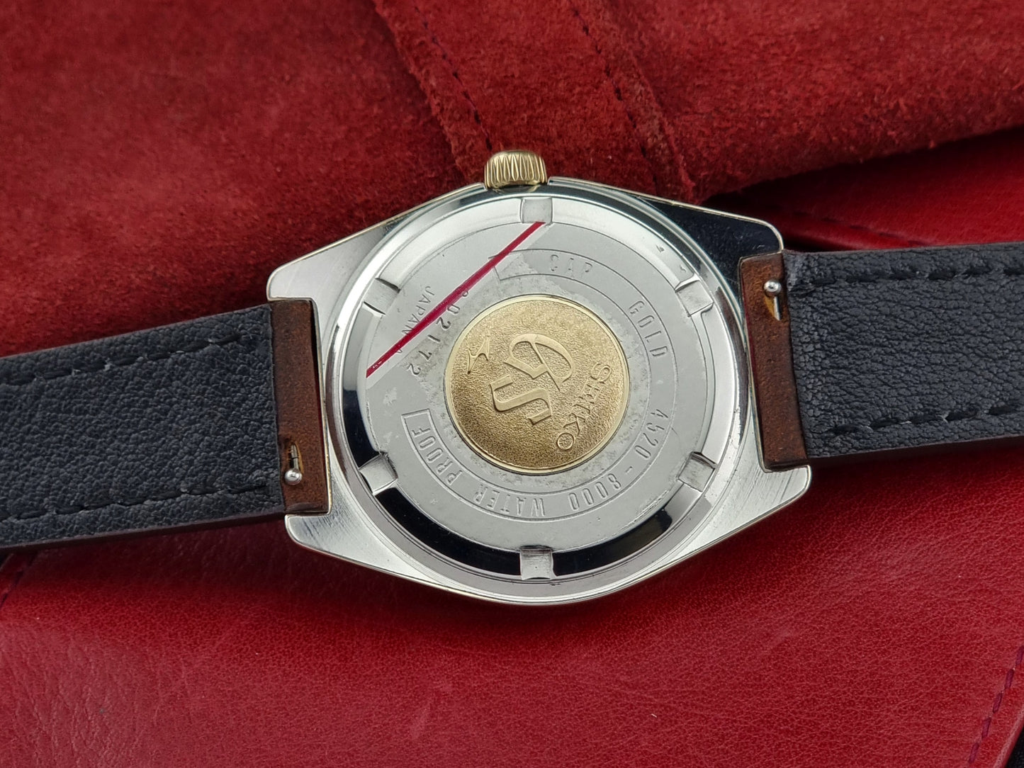 Vintage Grand Seiko 4520-8000 gold watch with brown leather strap on a dark background case back
