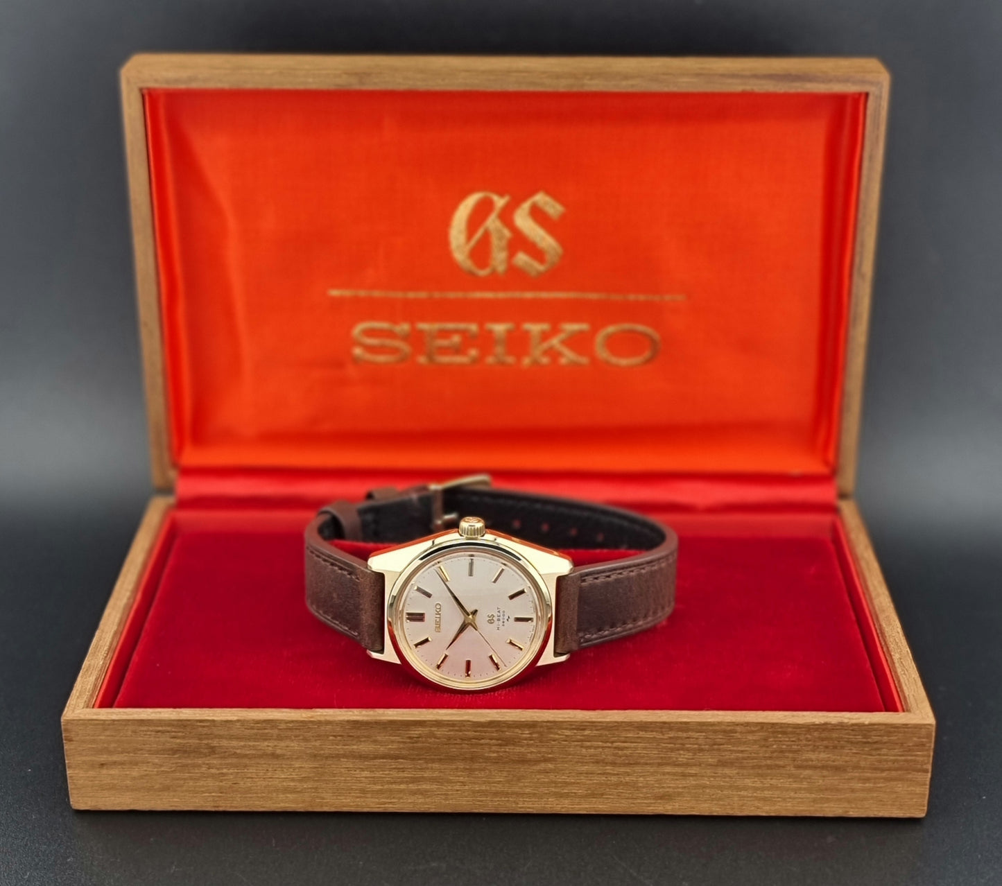 Vintage Grand Seiko 4520-8000 gold watch with brown leather strap on a dark background box view