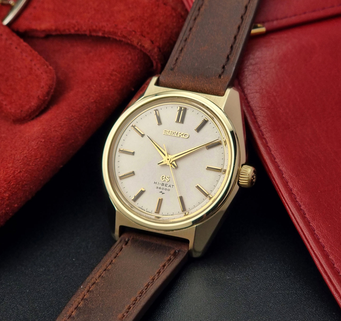Vintage Grand Seiko 4520-8000 gold watch with brown leather strap on a dark background crown view