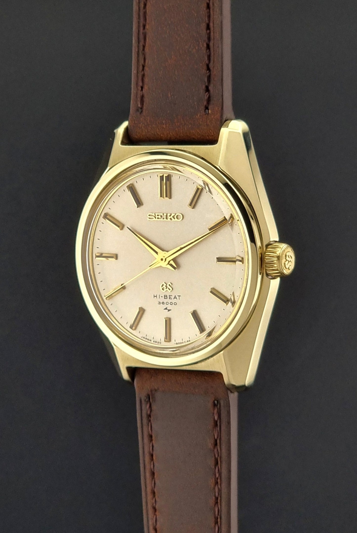 Vintage Grand Seiko 4520-8000 gold watch with brown leather strap on a dark background crown view