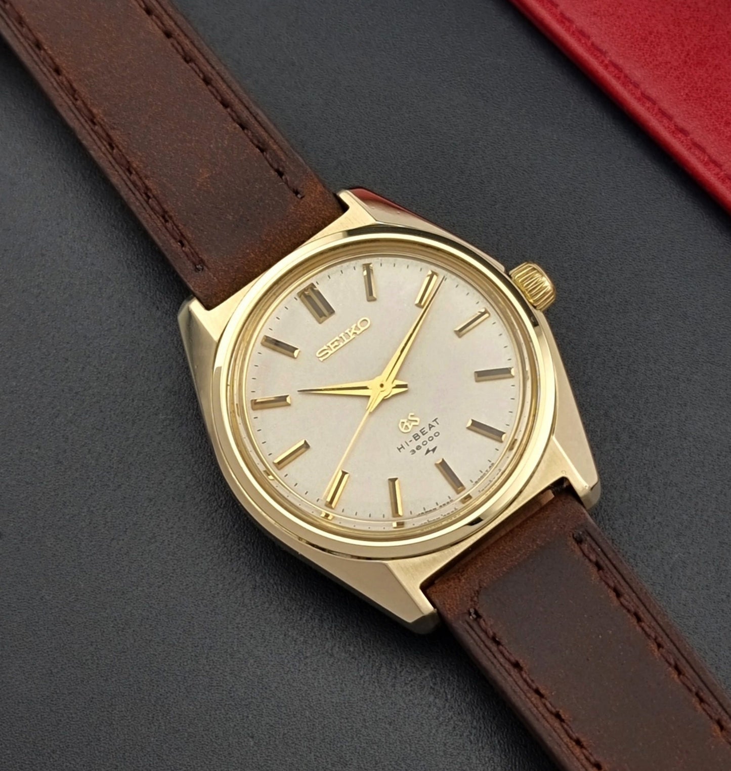 Vintage Grand Seiko 4520-8000 gold watch with brown leather strap on a dark background close up dial