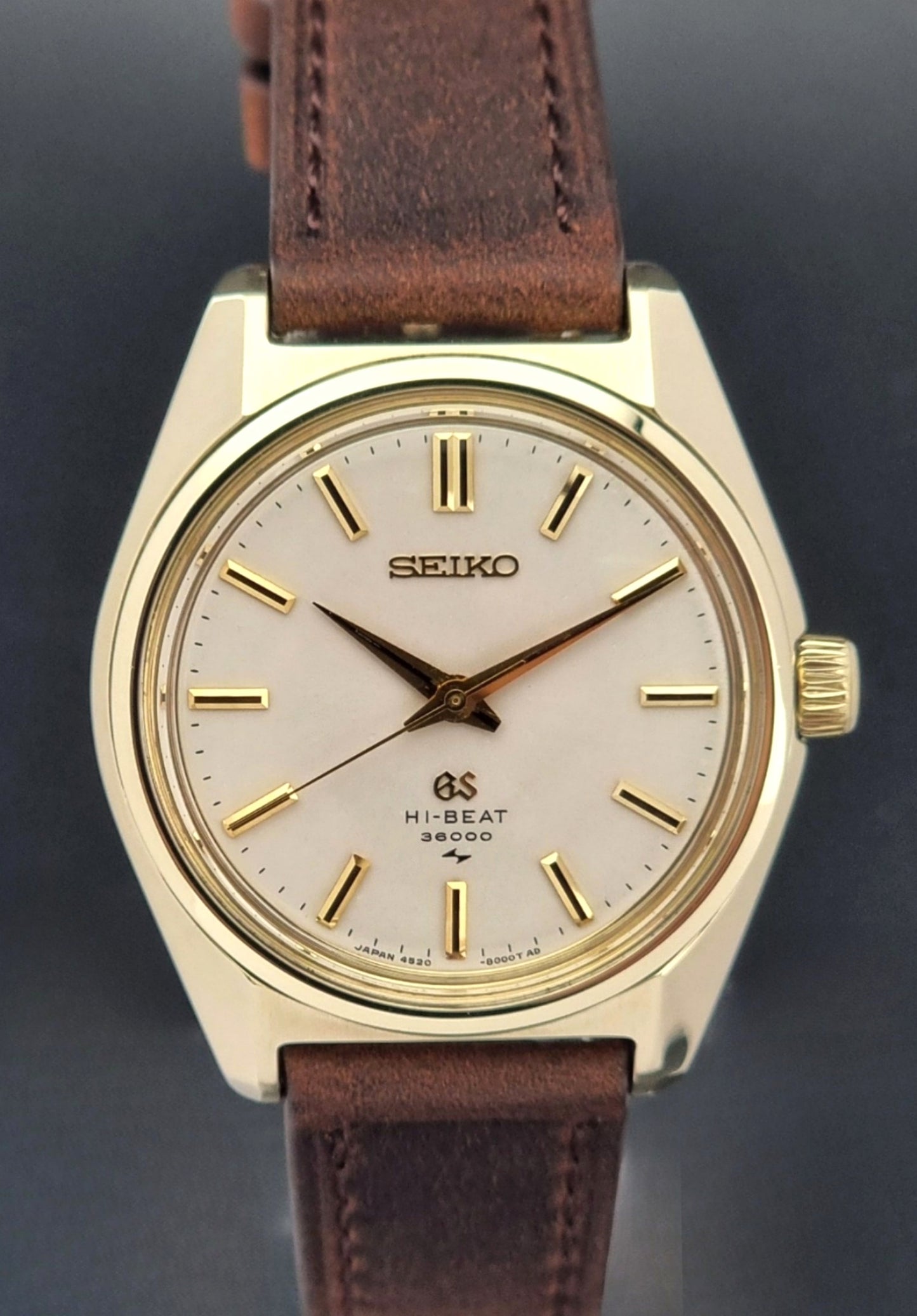 Vintage Grand Seiko 4520-8000 gold watch with brown leather strap on a dark background close up