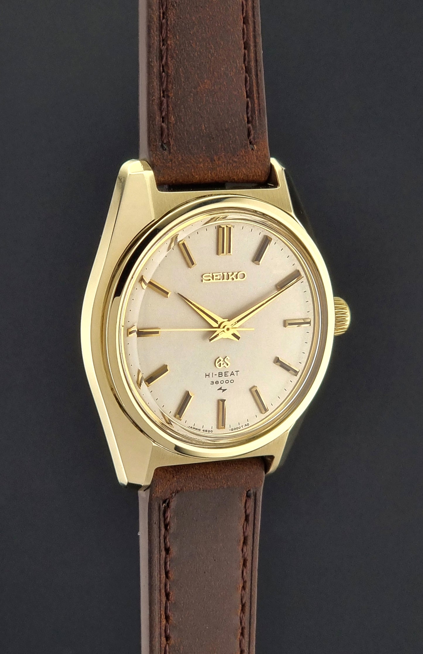 Vintage Grand Seiko 4520-8000 gold watch with brown leather strap on a dark background side profile