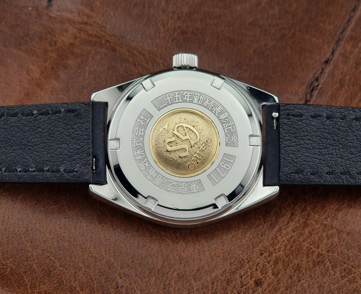 Vintage Grand Seiko 4520-8000 watch with black leather strap on a brown background case back