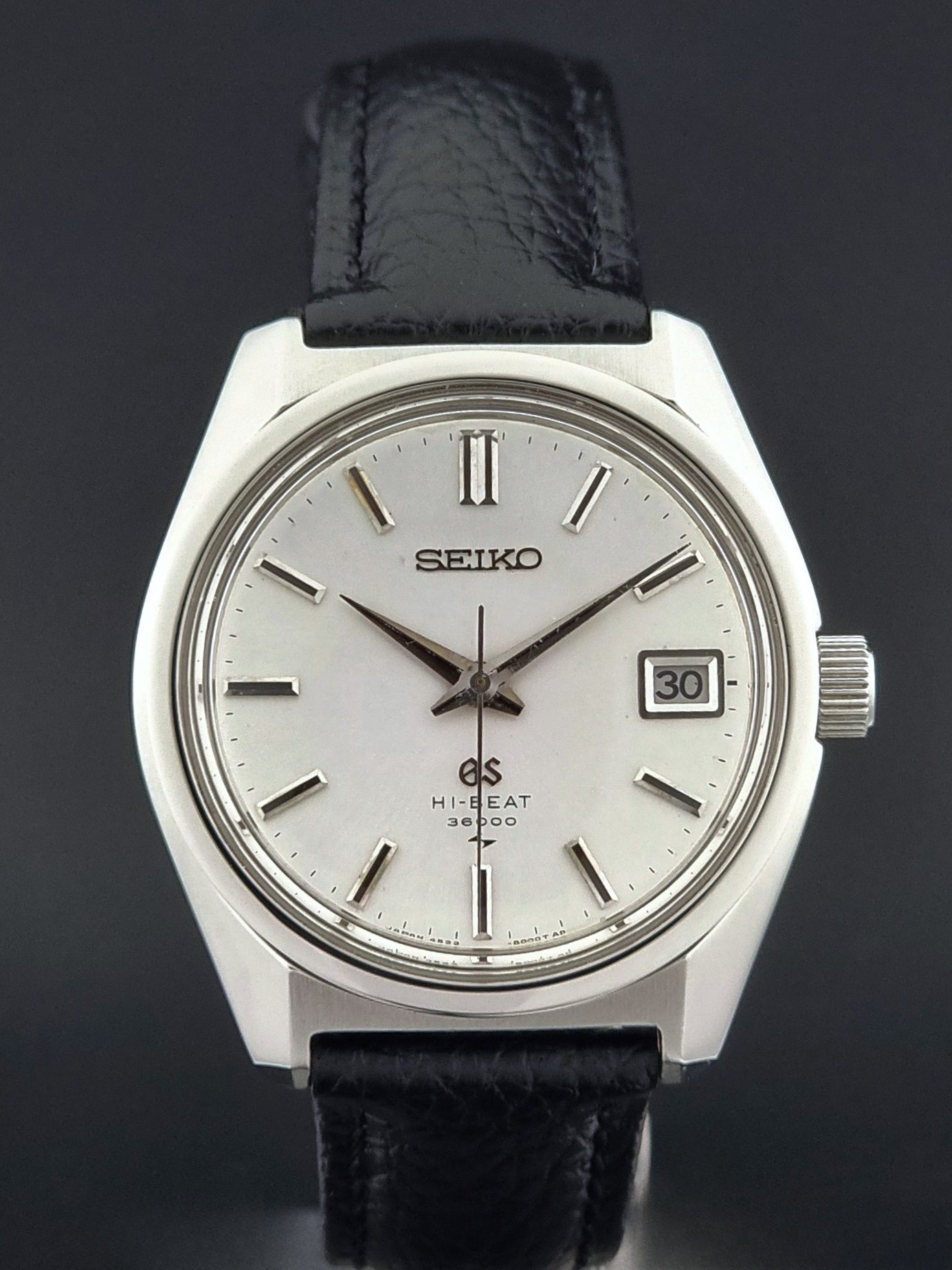 Vintage Grand Seiko watch with black leather strap on a dark background