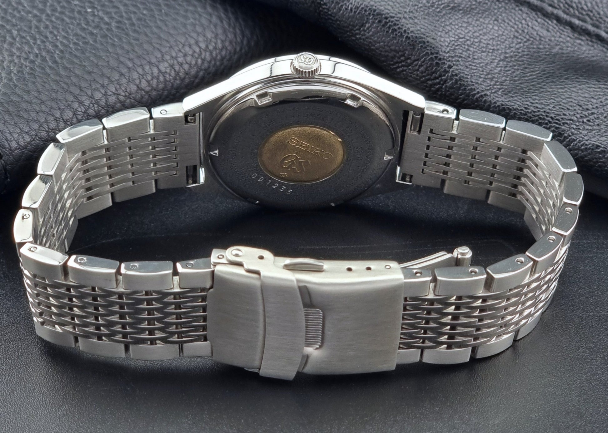 Vintage Grand Seiko Wristwatch 5646-7010 with a detailed band on a dark textured surface back view