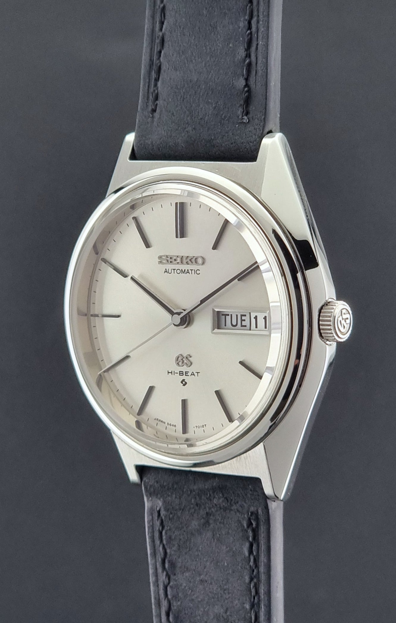 Vintage Grand Seiko watch with a silver case and black leather strap on a dark background