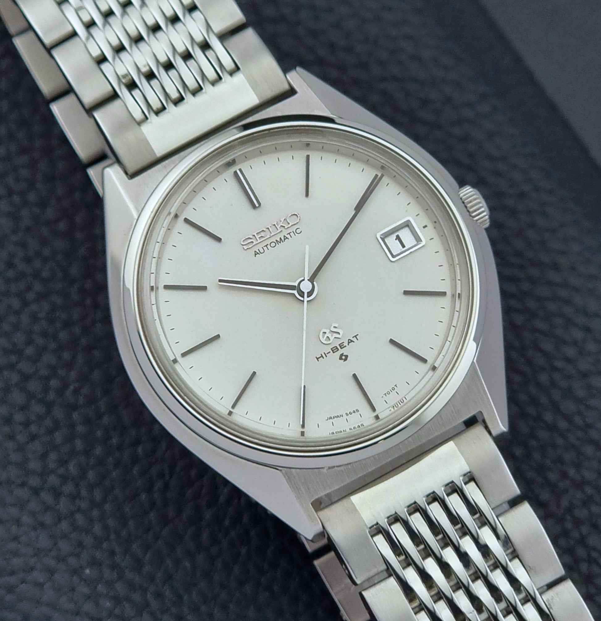 Vintage Grand Seiko Wristwatch 5646-7010 with a white face on a dark textured background close up