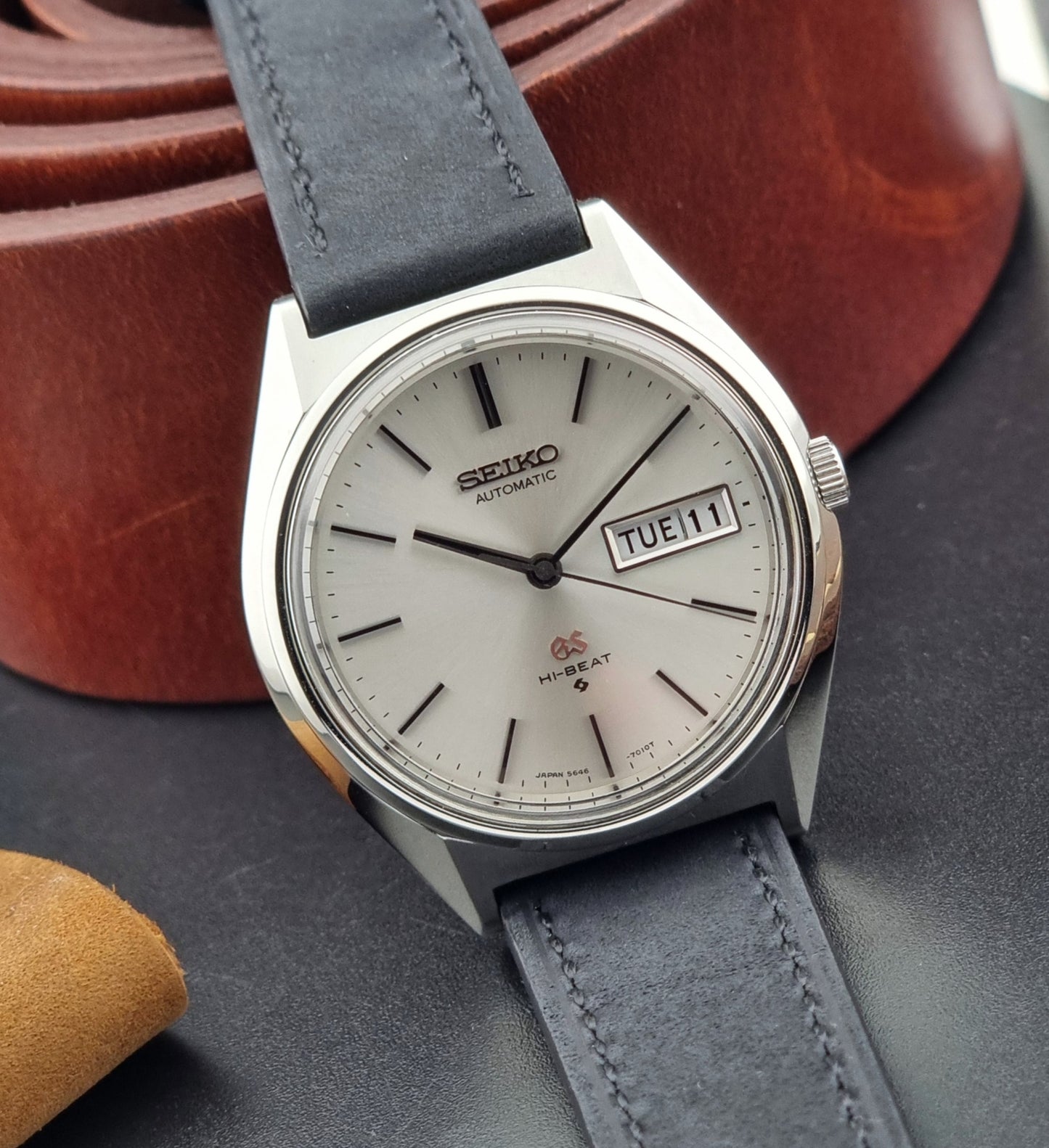 Vintage Grand Seiko watch with a black strap on a dark surface