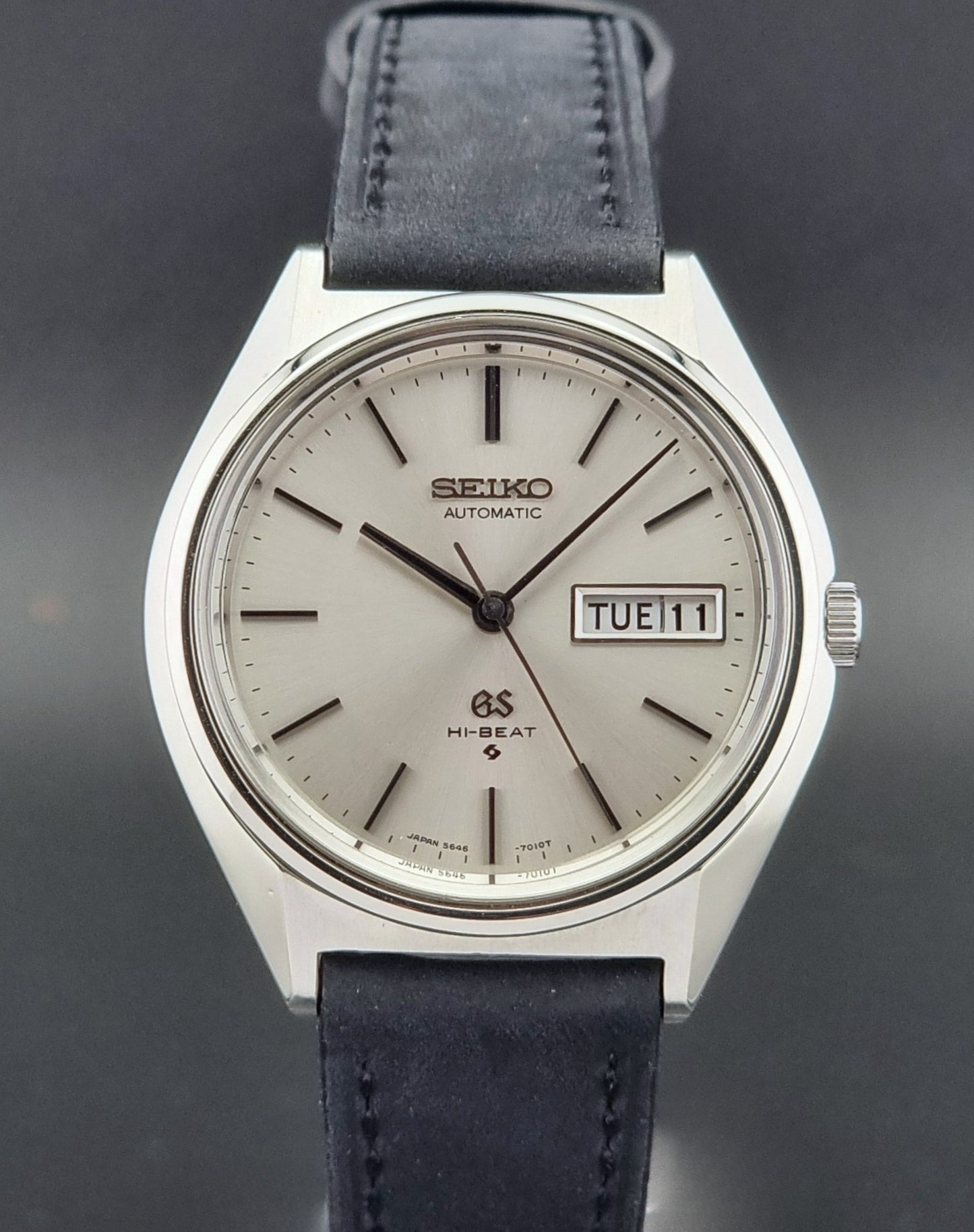 Vintage Grand Seiko watch with a dark black leather strap on a dark background
