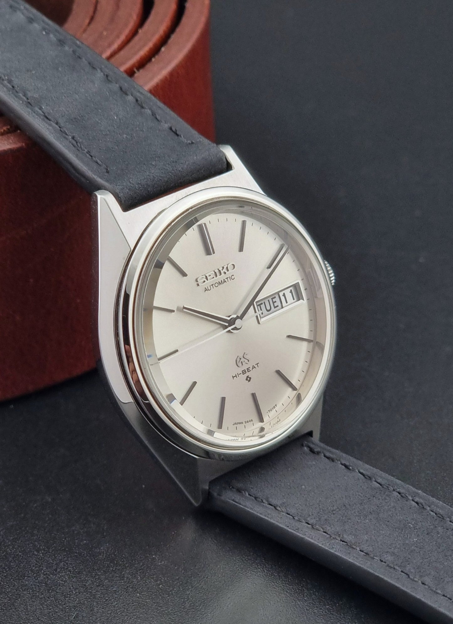 Vintage Grand Seiko watch with black leather strap on a dark background