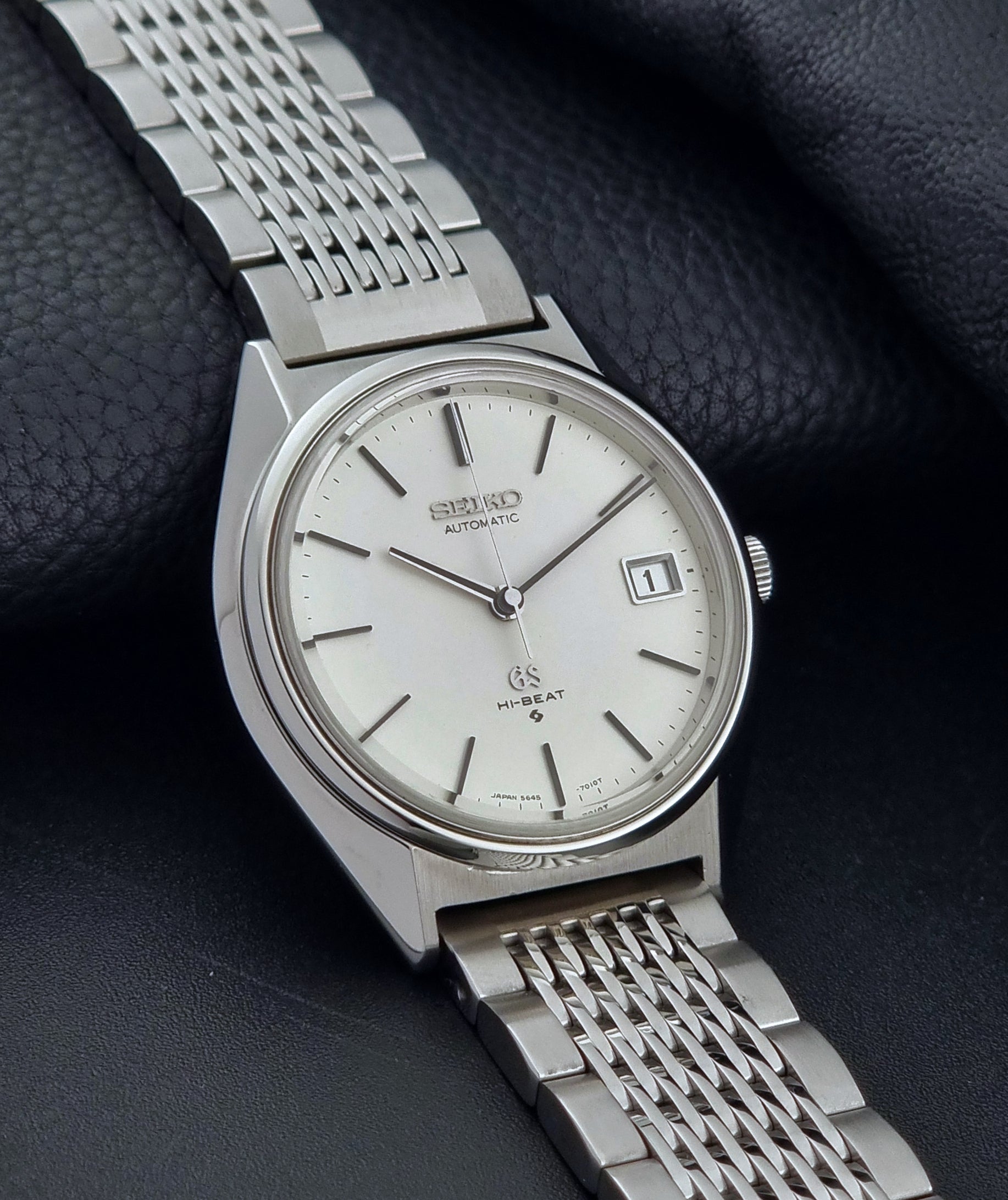 Vintage Grand Seiko Wristwatch 5646-7010 with a white face on a dark textured background side view