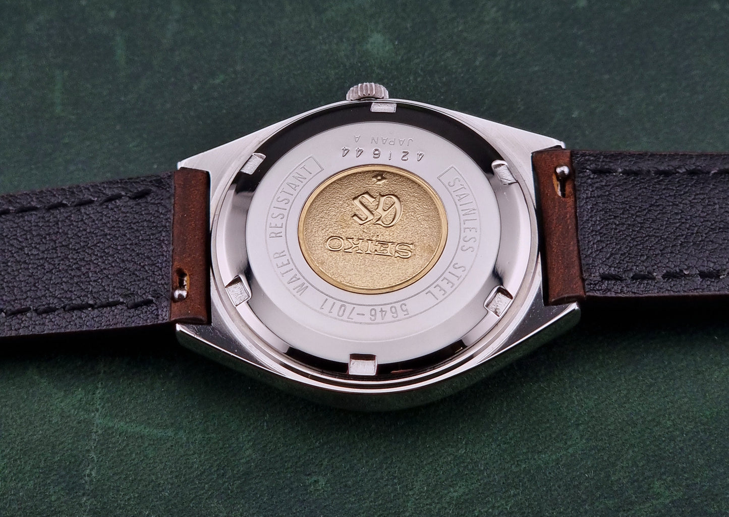 Close-up of the back of a Vintage Grand Seiko Watch with a visible brand logo on a green background