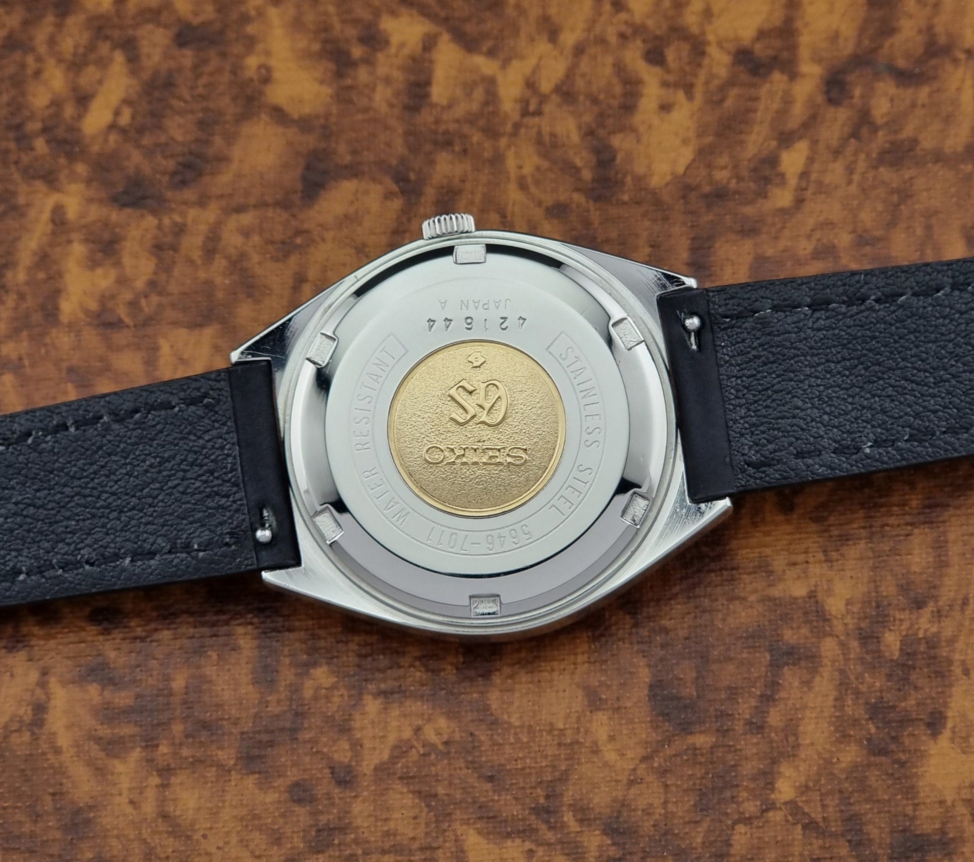 Vintage Grand Seiko 5646-7011 Wristwatch with black leather strap on a wooden surface case back
